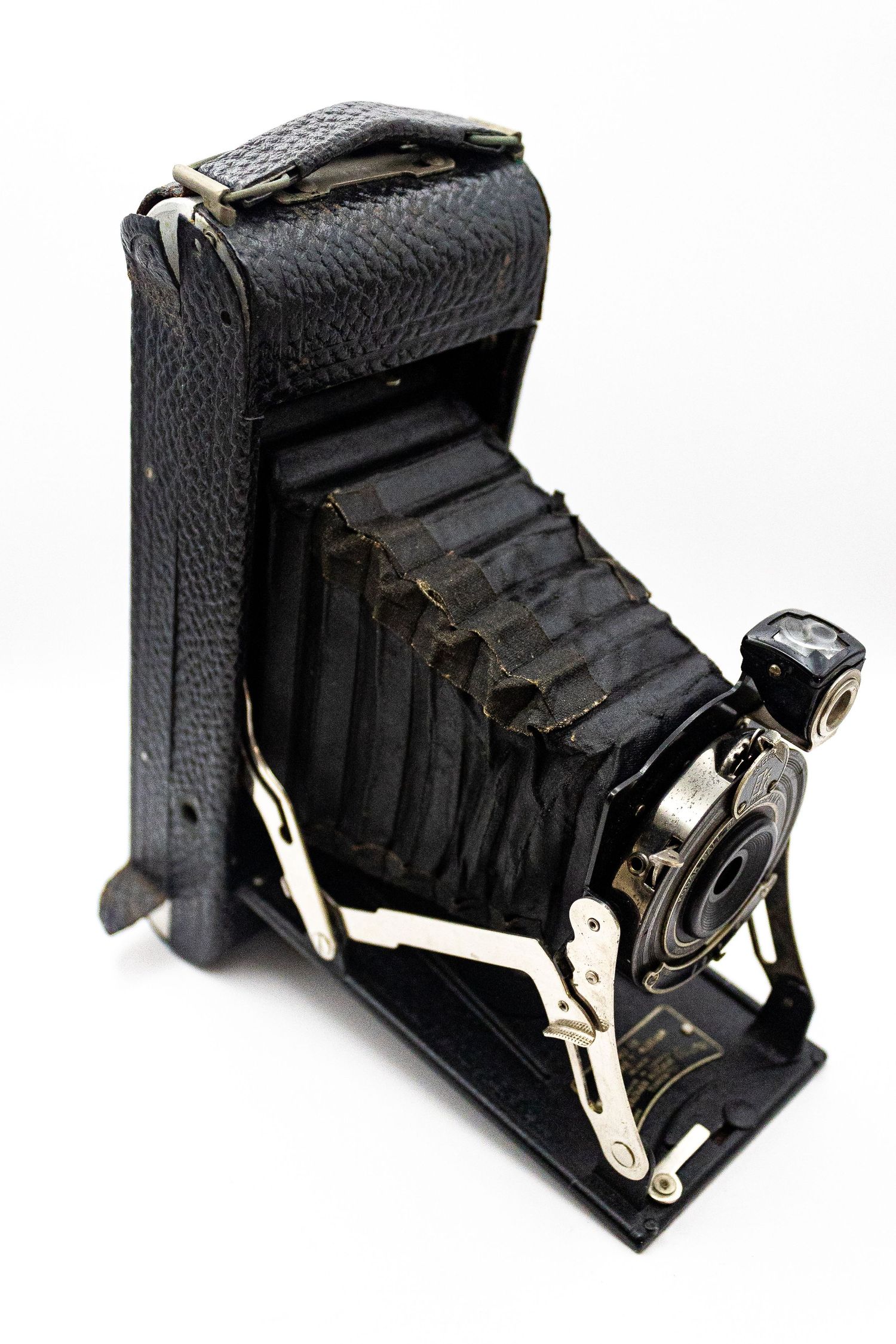 Vintage black folding bellows camera with leather case on white background.