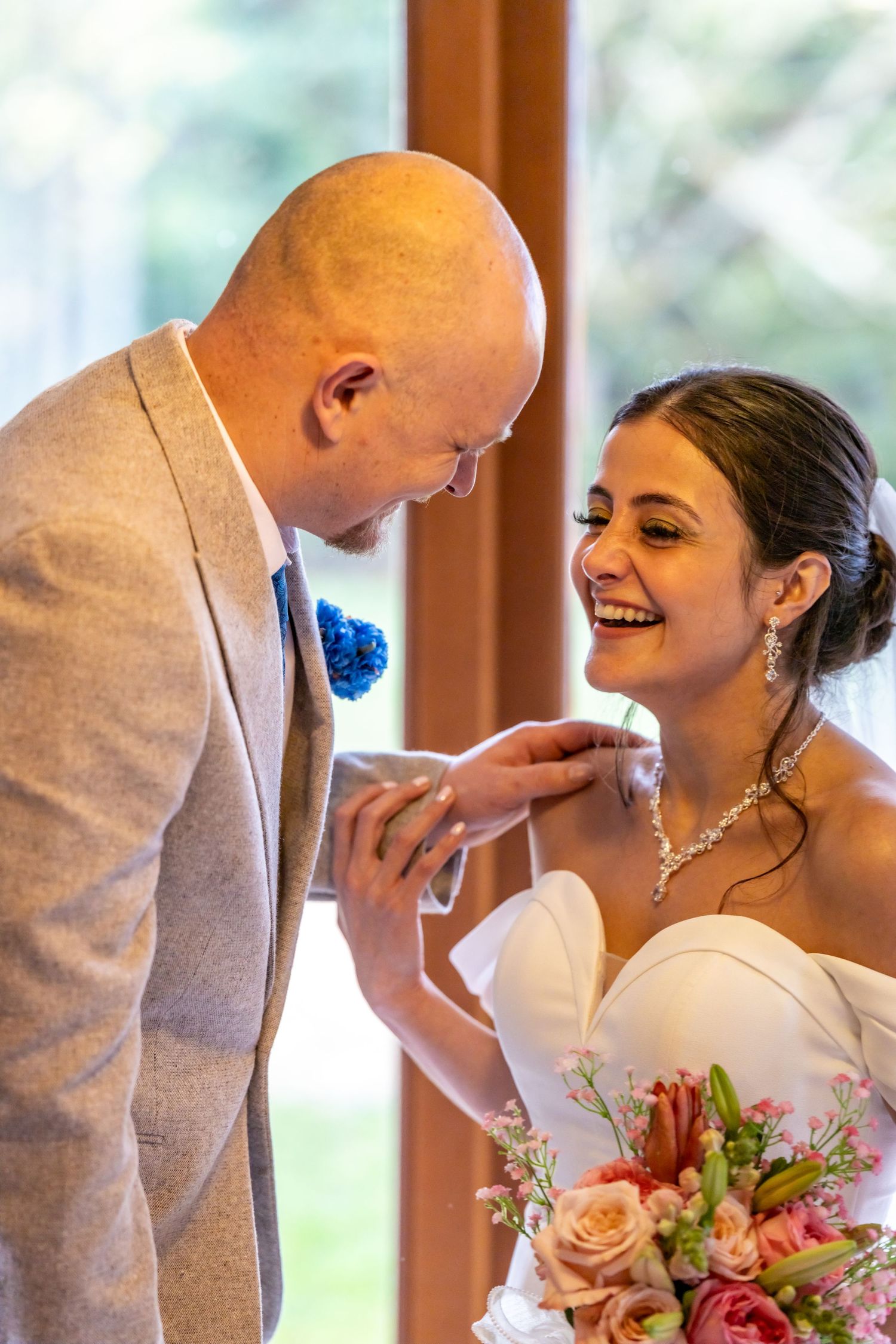 A groom and his laughing bride on their wedding day sharing a special moment.