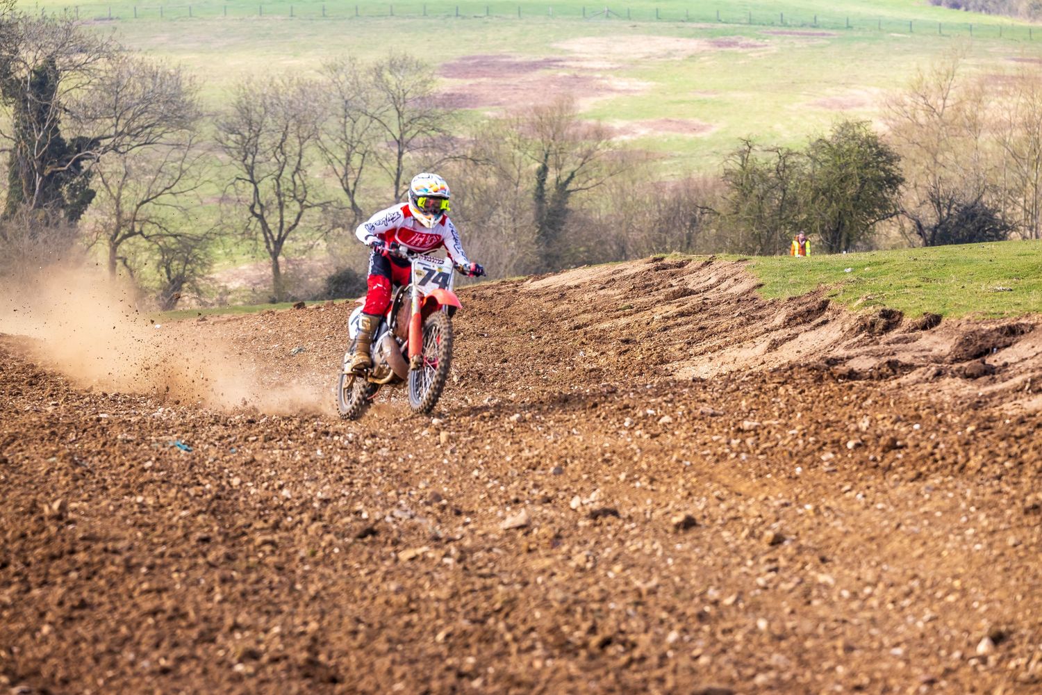 Motocross rider racing on a dirt track, kicking up dust on a rugged off-road course, epic moment photographed by Roddy.