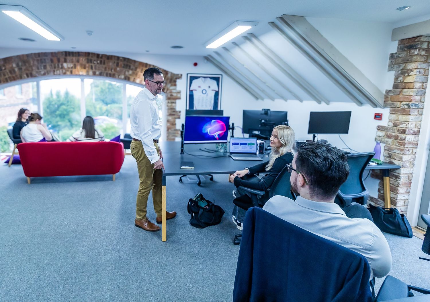 Team of professionals collaborating in a modern office space with exposed brick and arched ceiling.