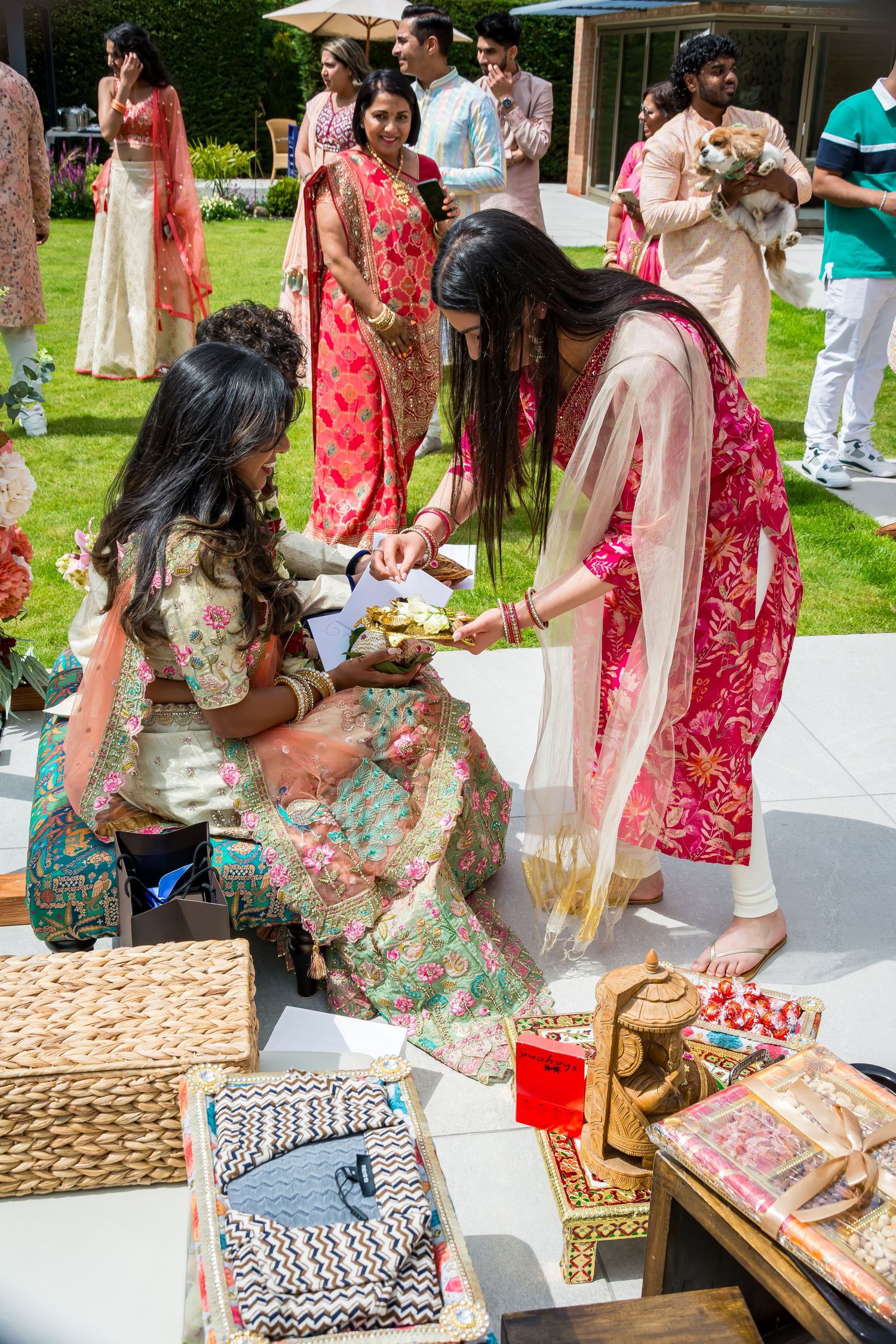 Guests in colorful traditional Indian attire exchanging gifts at an outdoor wedding ceremony.