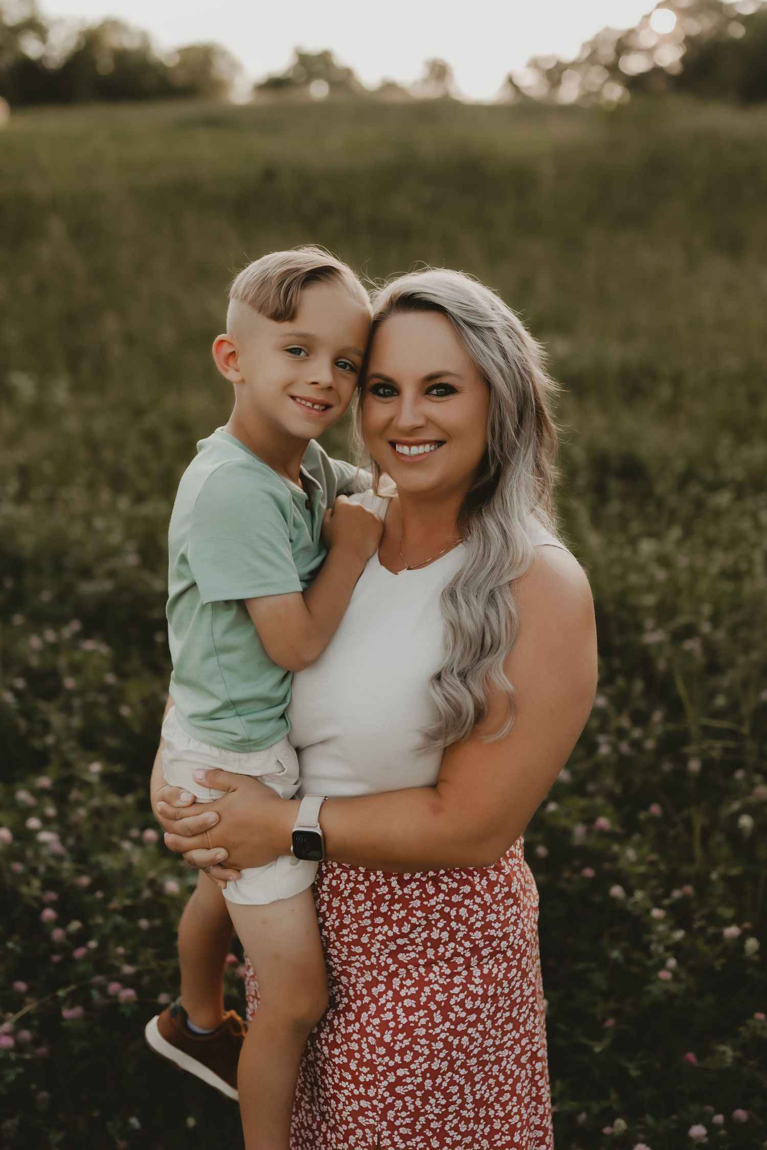 A sweet outdoor photoshoot in a wildflower field at golden hour shows tender moments between parent and child.