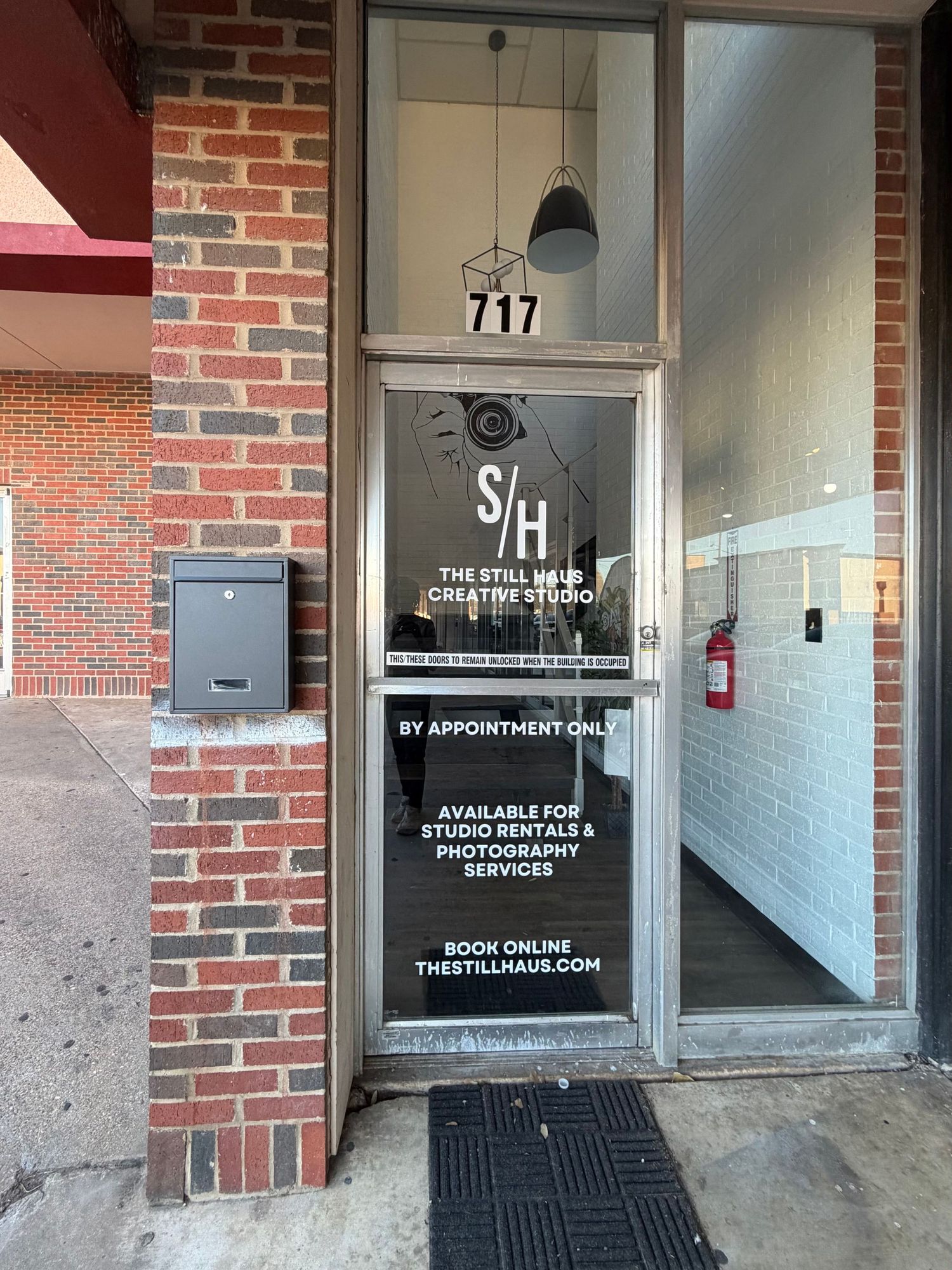Glass door entrance to The Still Haus Creative Studio at 717, offering studio rentals and photography services by appointment.