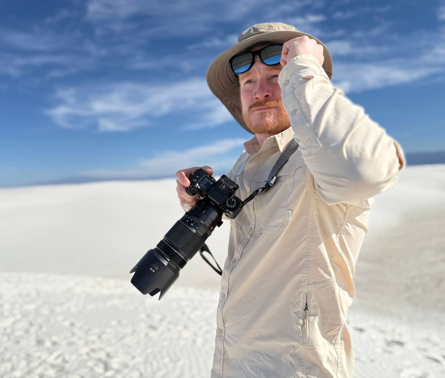 Photographer Danny Damiani walks in the sand dunes of White Sands National Park with a camera.