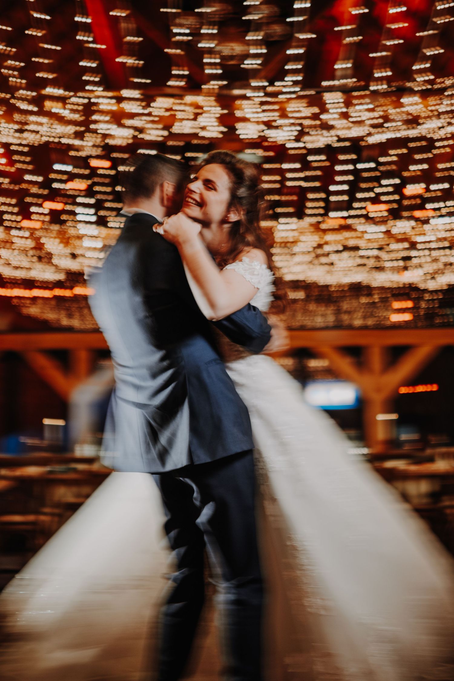 Bride and groom share their first dance, surrounded by warm bokeh lights at a romantic wedding reception.