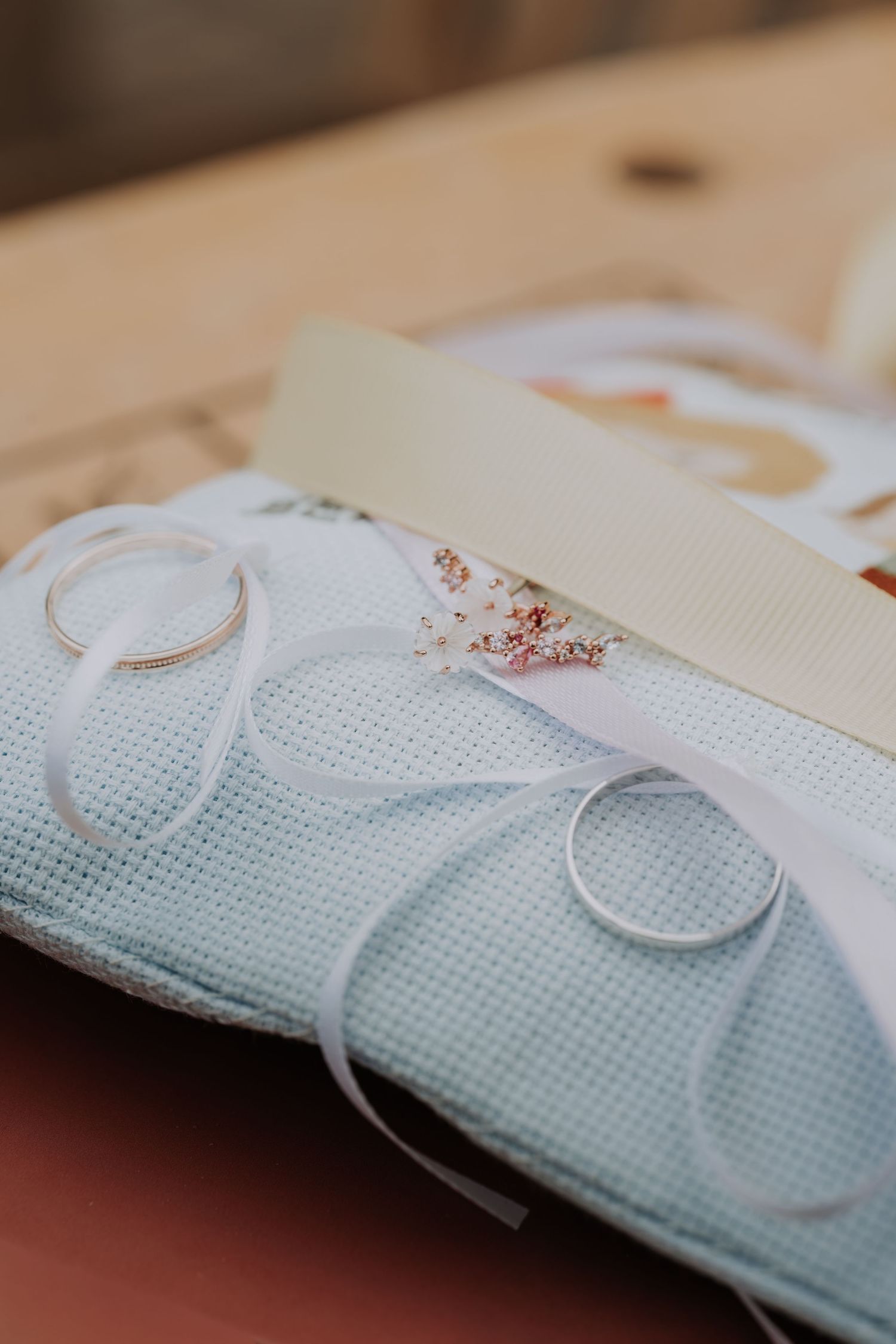 Two wedding rings resting on a light blue ring bearer pillow tied with white ribbon.