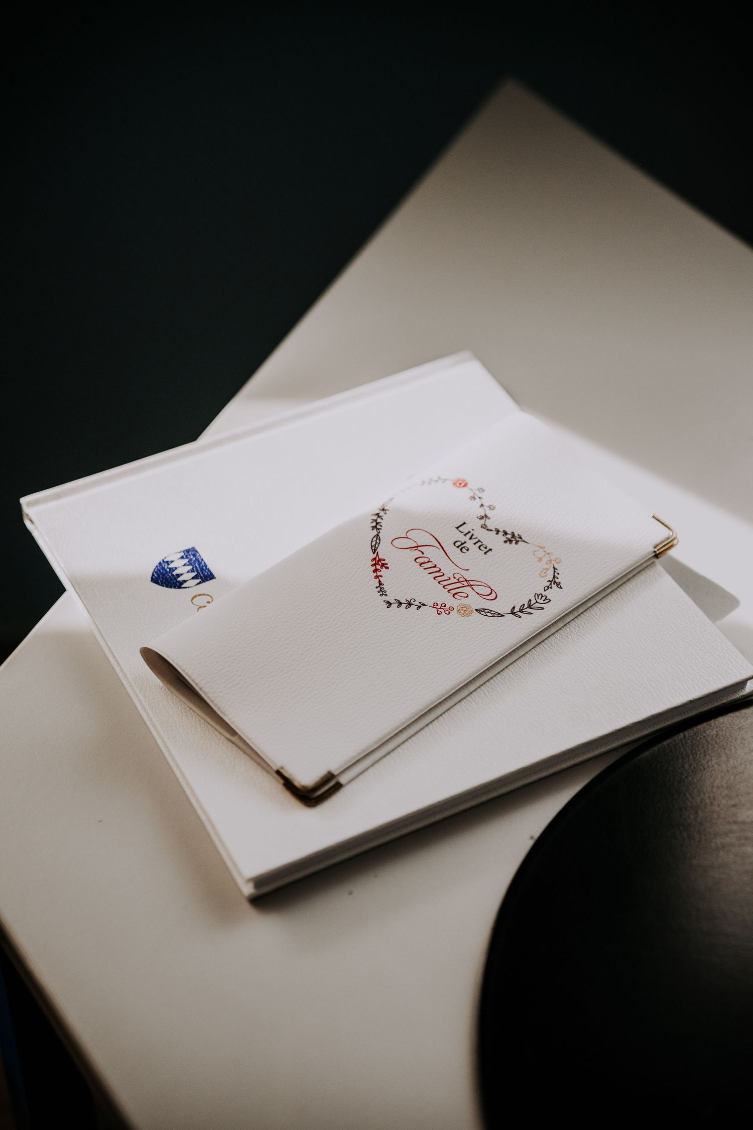 White wedding guest book with floral heart design and pen on a table.