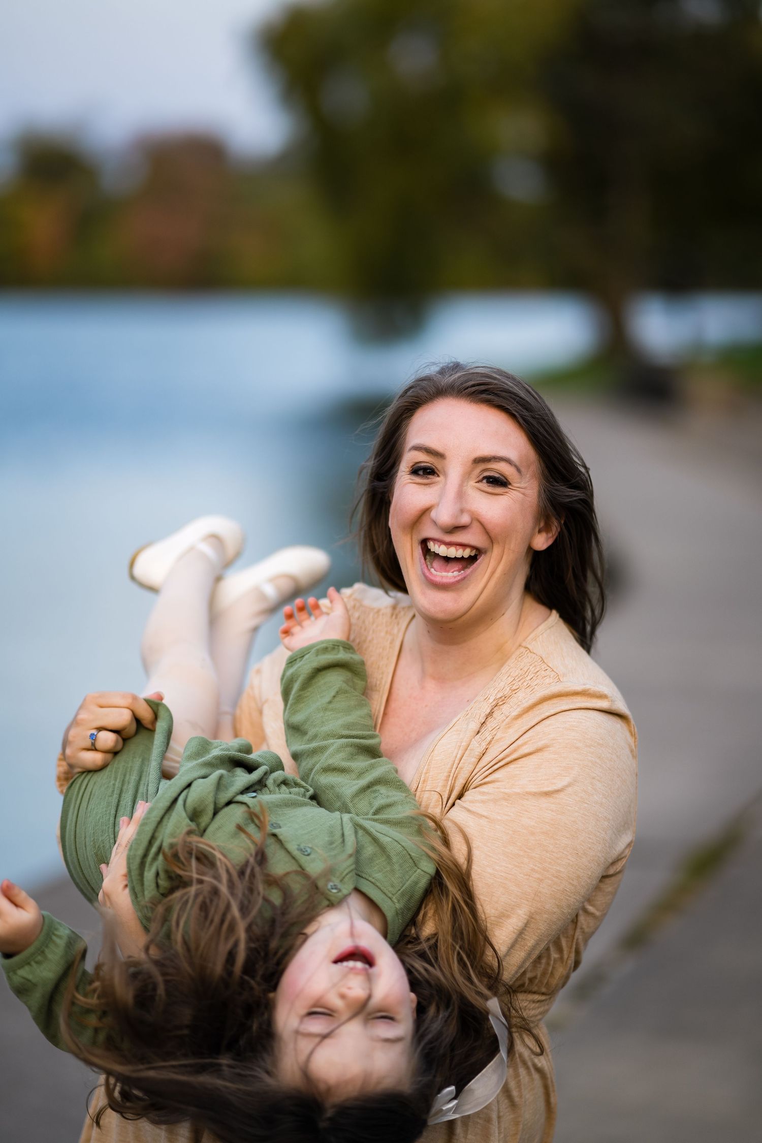 A playful outdoor portrait capturing joyful laughter and movement near a lake.