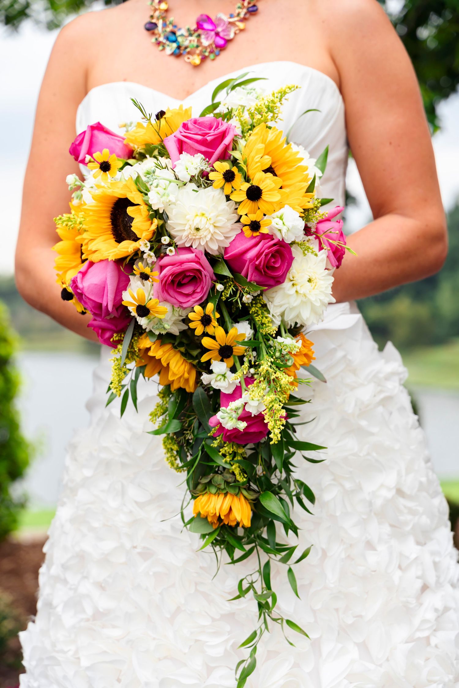 A wedding portrait of a colorful wedding day bouquet with pink roses and sunflowers.