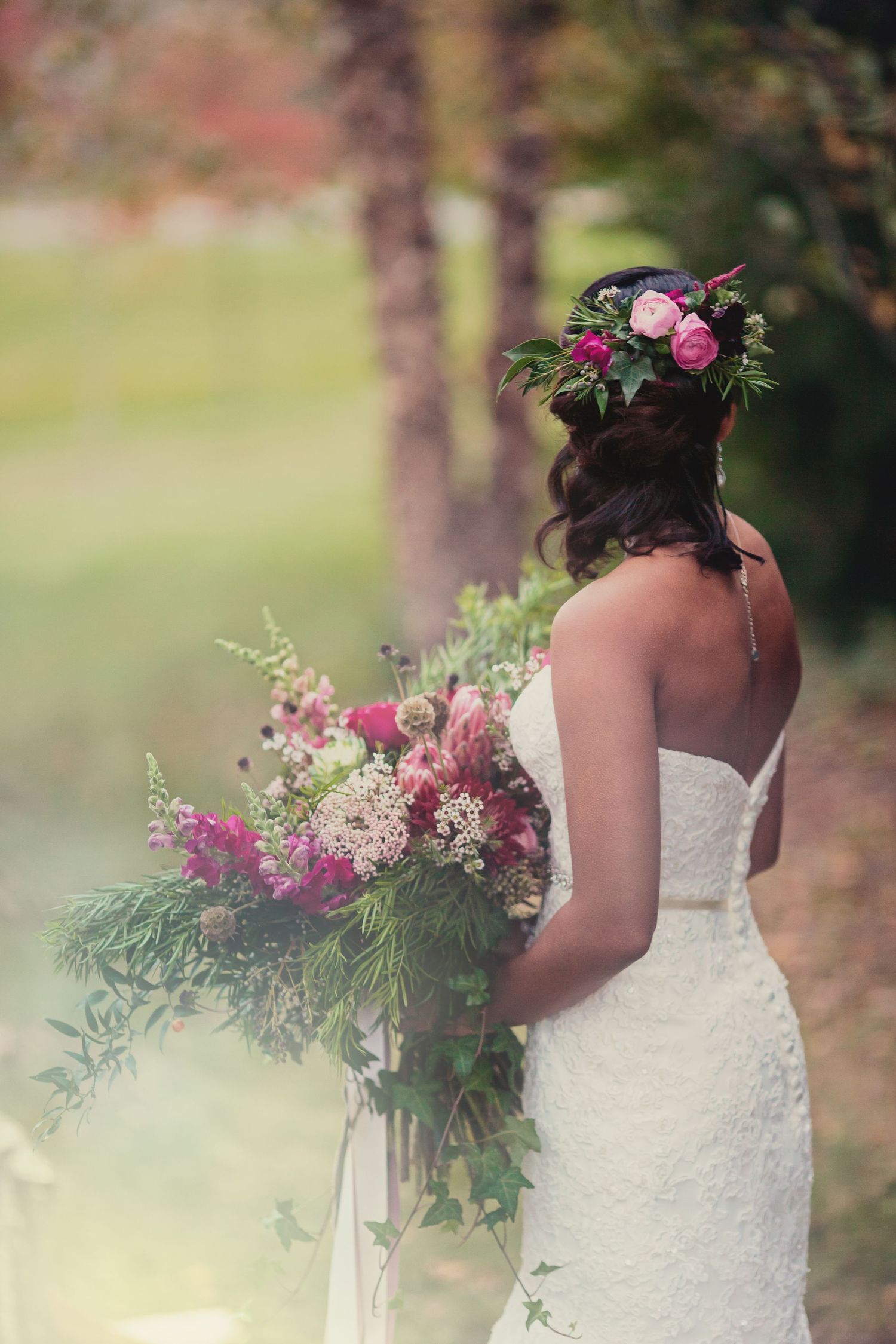 A bride holding an oversized rustic boho wedding bouquet showing the matching floral hair piece in her half-up style.