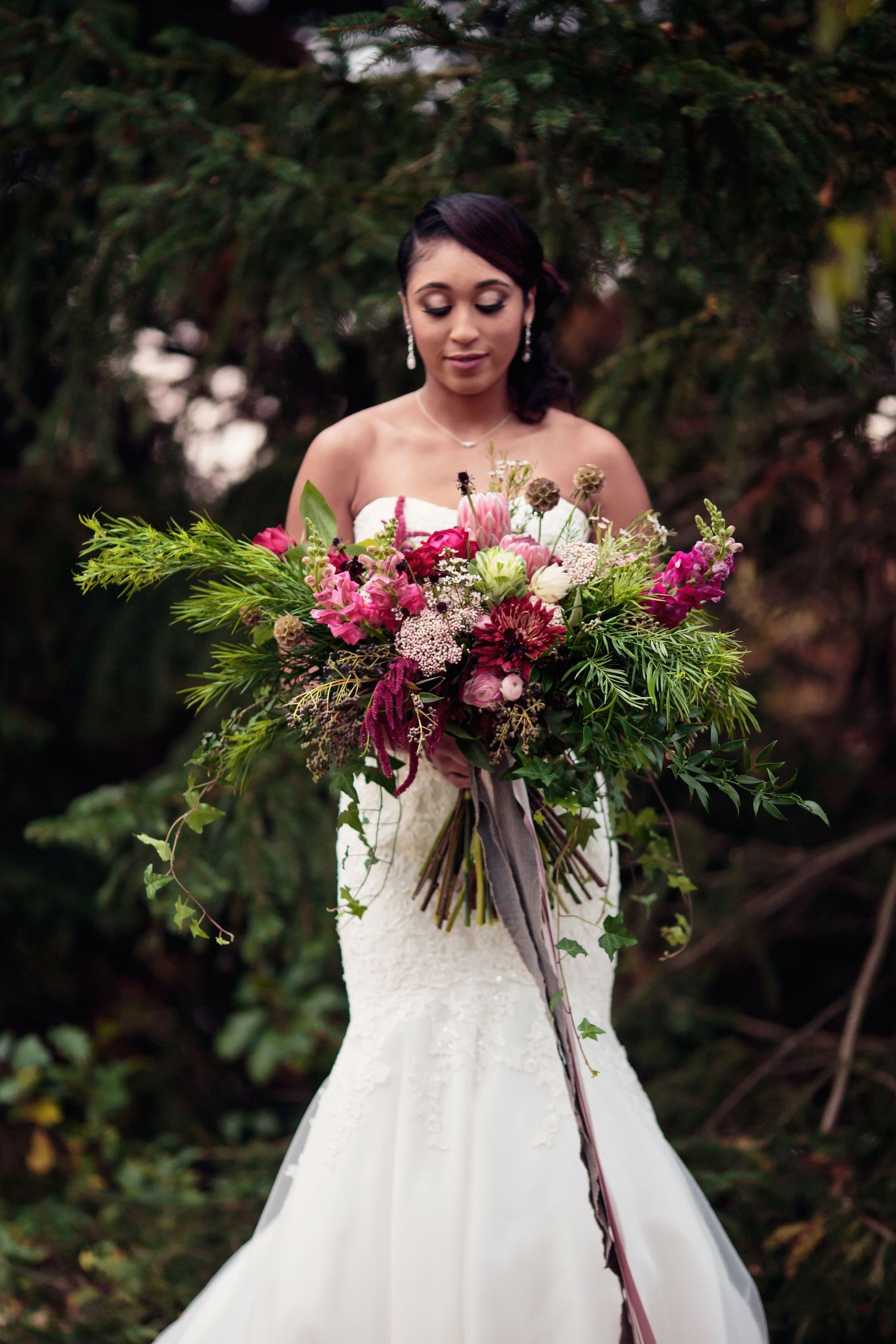 A modern Black bride in a fit-and-flare white bridal gown holding an oversized rustic boho wedding bouquet.