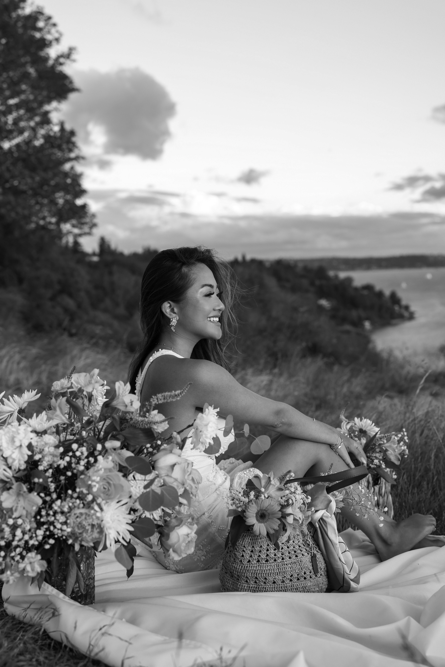 A black and white photo of a sunset picnic scene with flowers and coastal views.