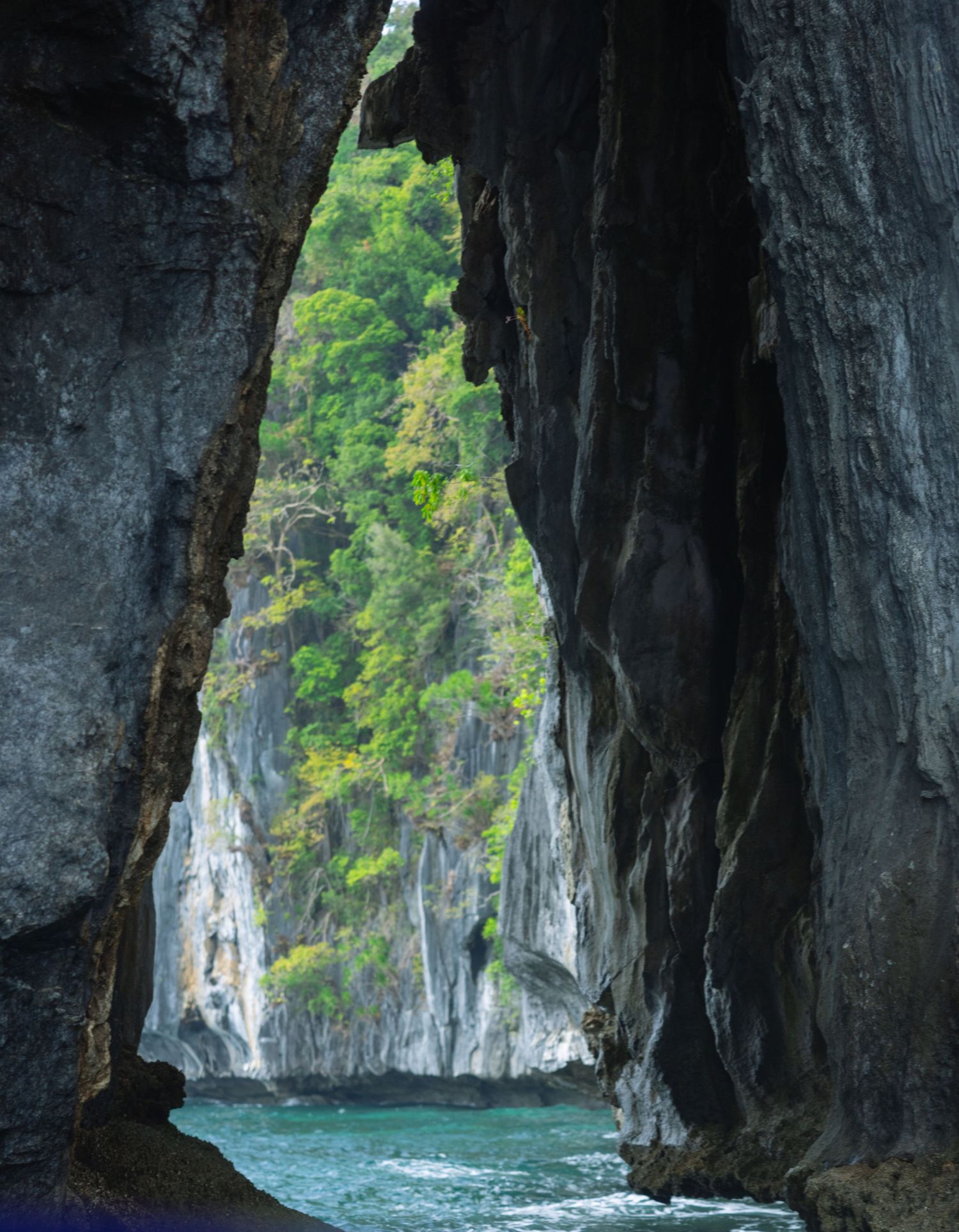 Natural rock formation creating a cave window to turquoise waters and limestone cliffs.