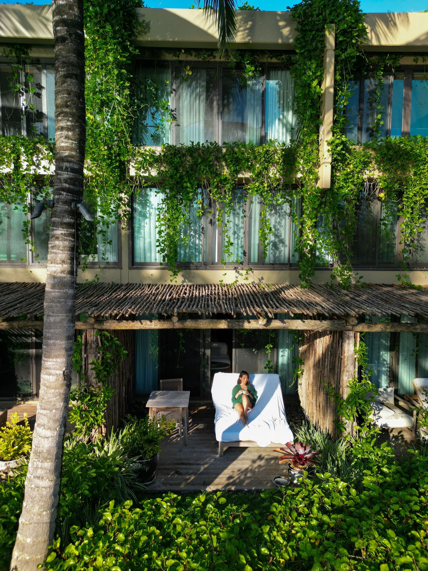 Tropical resort building covered in lush green vines with a peaceful patio space.