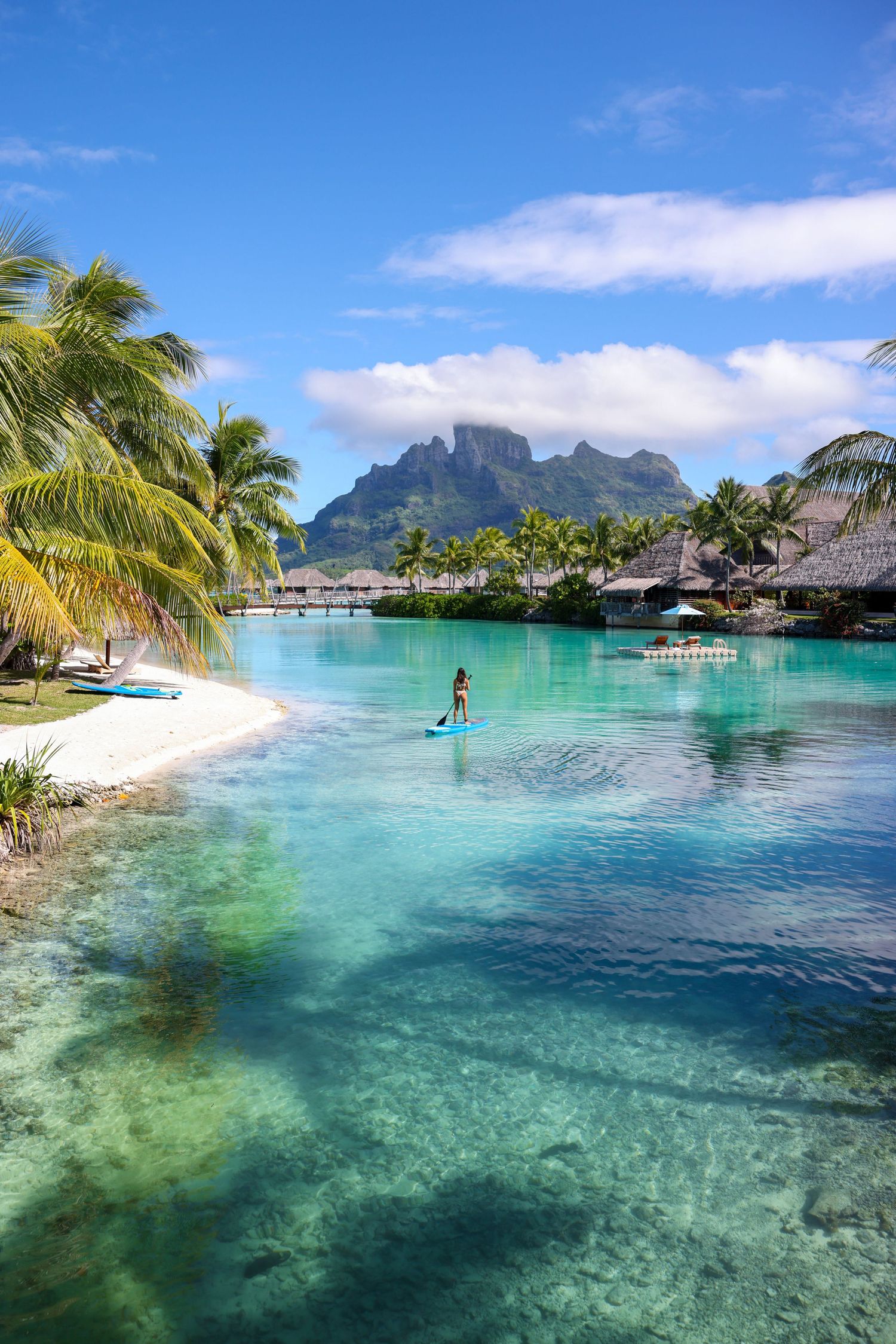 Tropical paradise with overwater bungalows, palm trees and crystal clear turquoise lagoon.