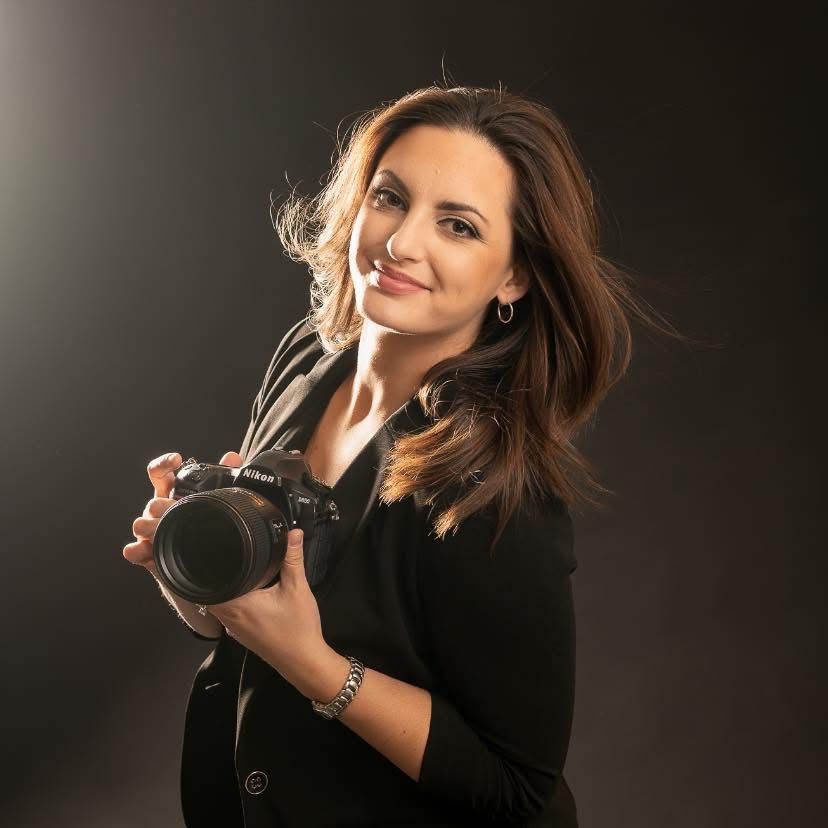 Woman in black top poses elegantly against dark background in professional studio photoshoot series.