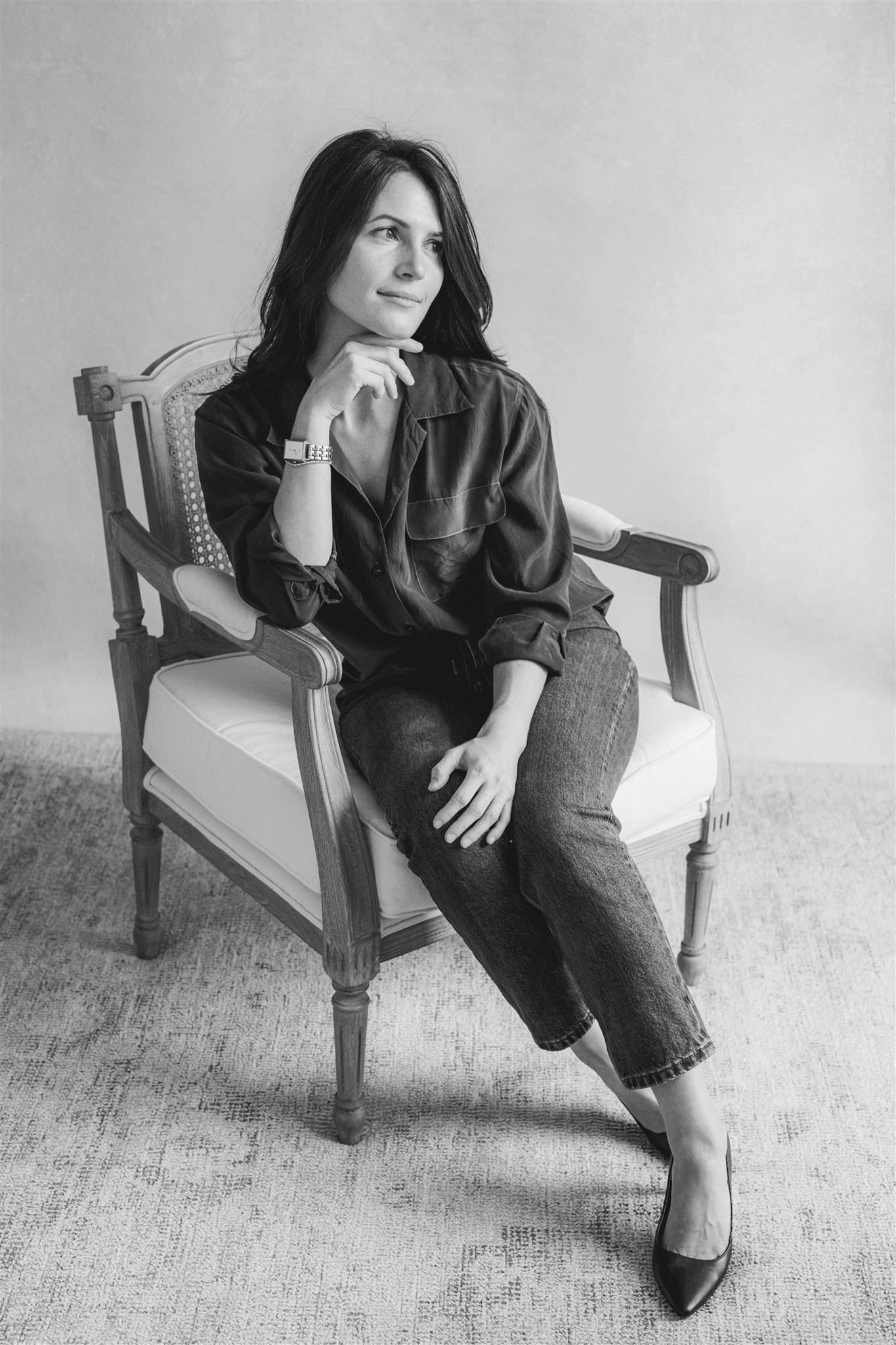 Black and white photo series showing someone seated in a wooden chair wearing dark clothing and striking different casual poses.