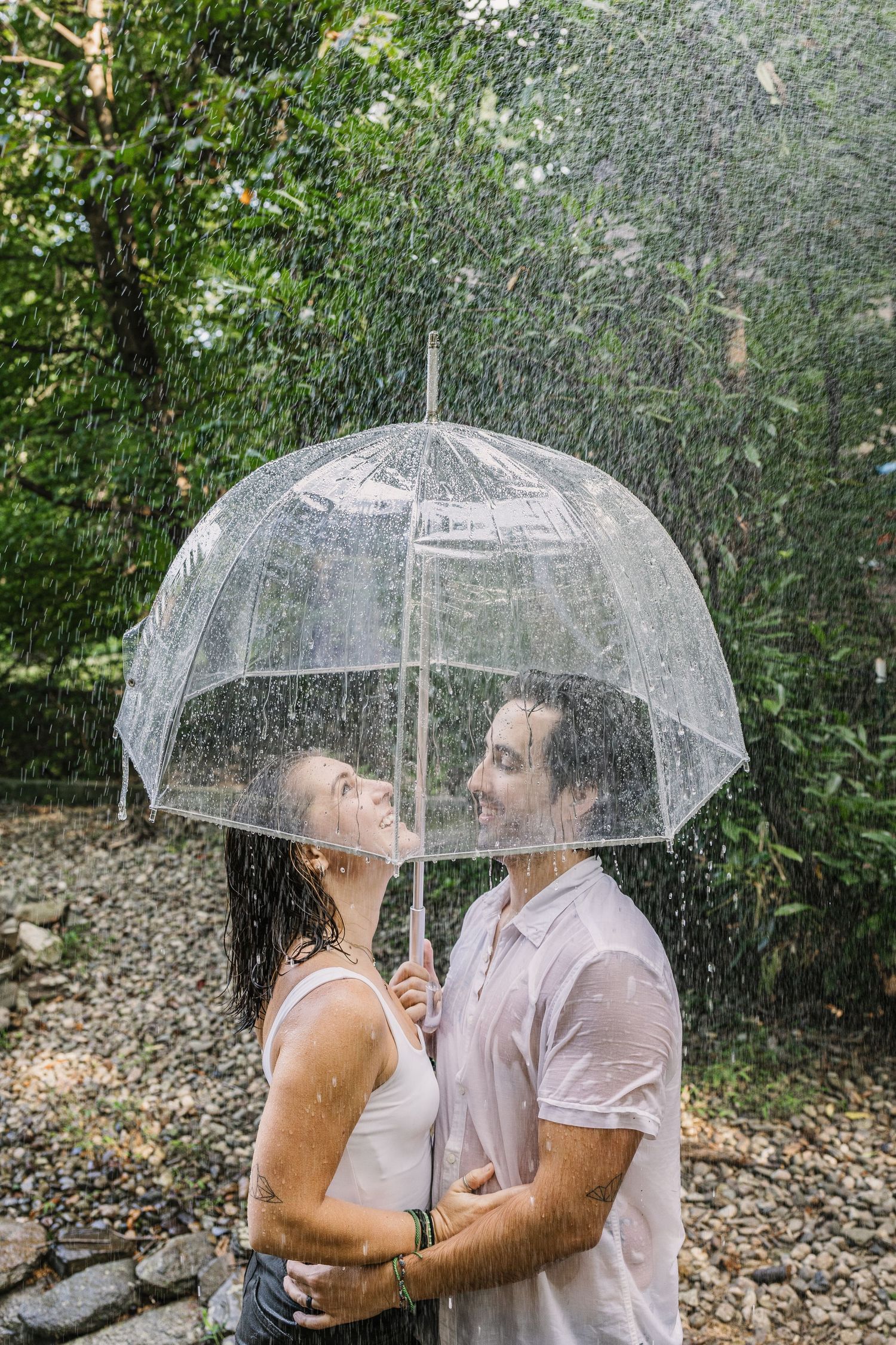 Couple kissing under a clear umbrella in the rain during a romantic outdoor couples photography session in Pennsylvania