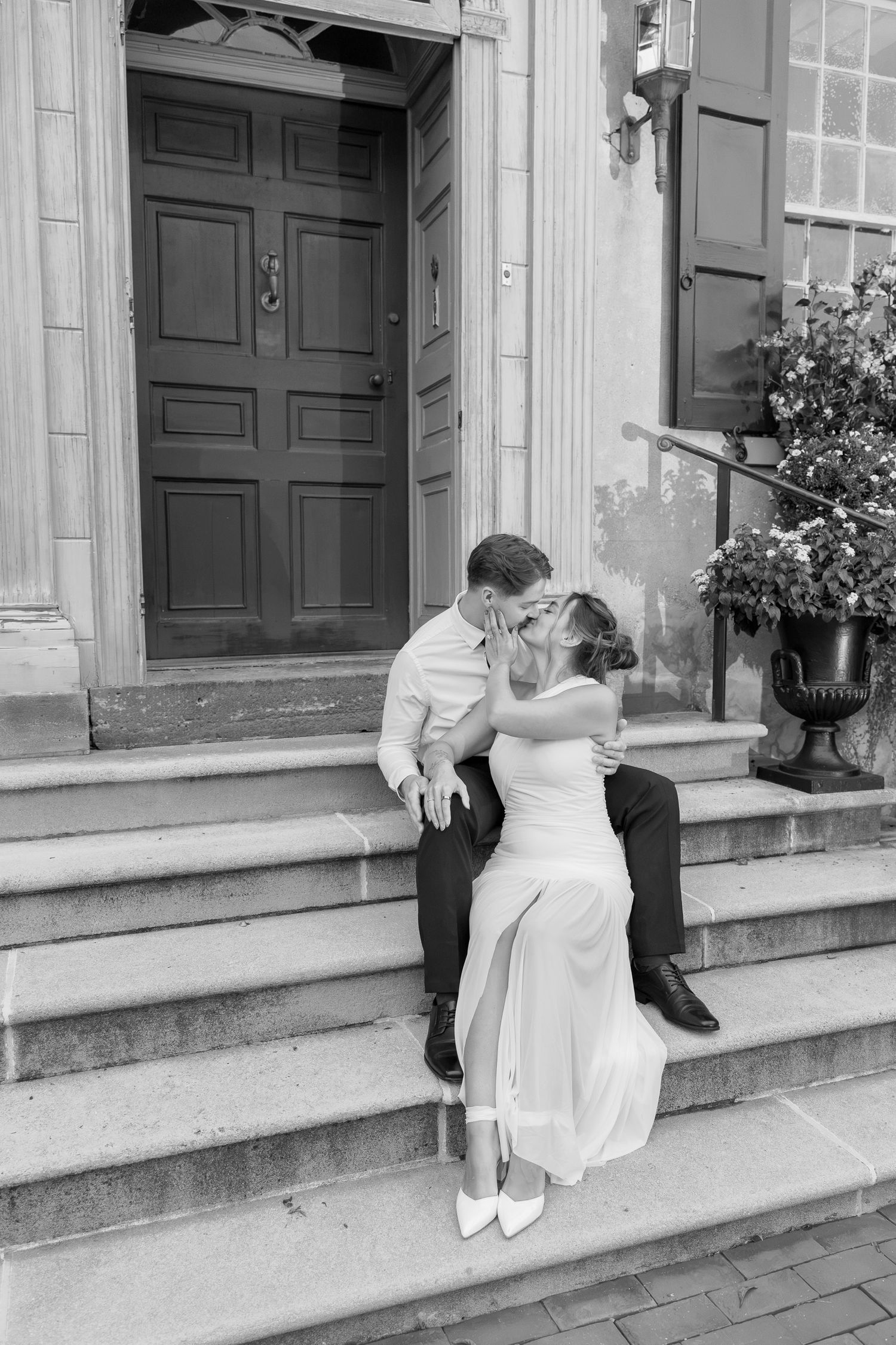 Engaged couple sitting together on the steps outside the distinctive blue and gold entrance at Conestoga House and Gardens in Lancaster, PA