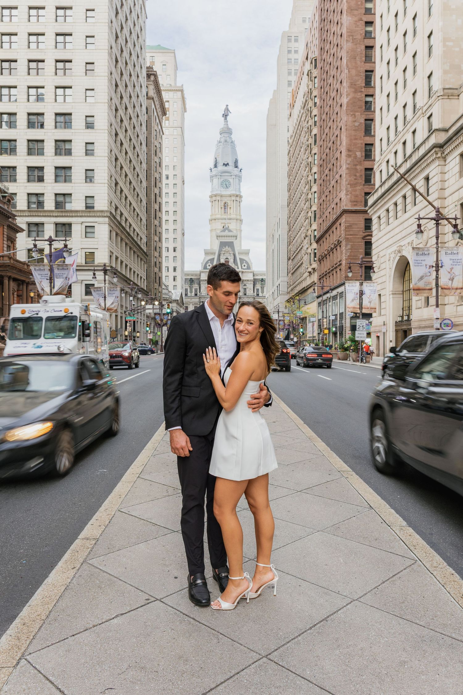 Couple embracing on a Center City Philadelphia sidewalk during their engagement session near historic City Hall.