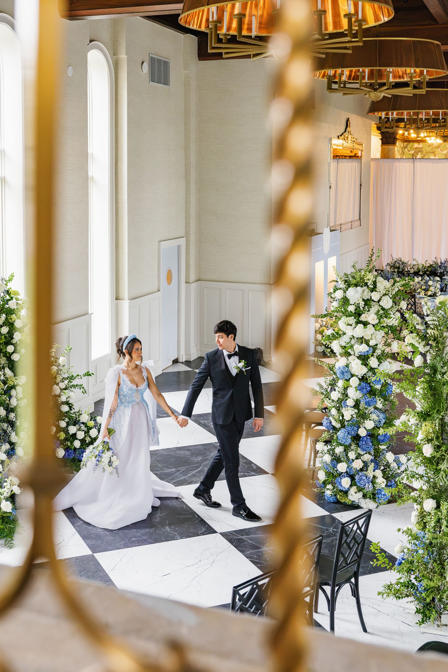 Bride and groom walking through an ornate interior at Elkins Estate, a historic Philadelphia-area wedding venue.