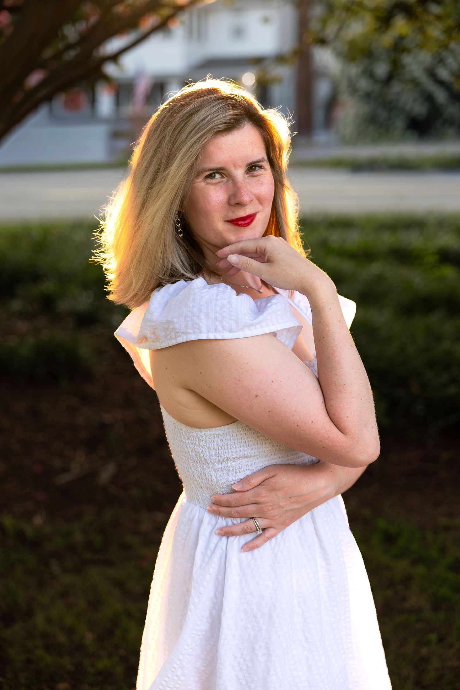Woman posing outdoors in a white dress during a natural light lifestyle portrait photography session
