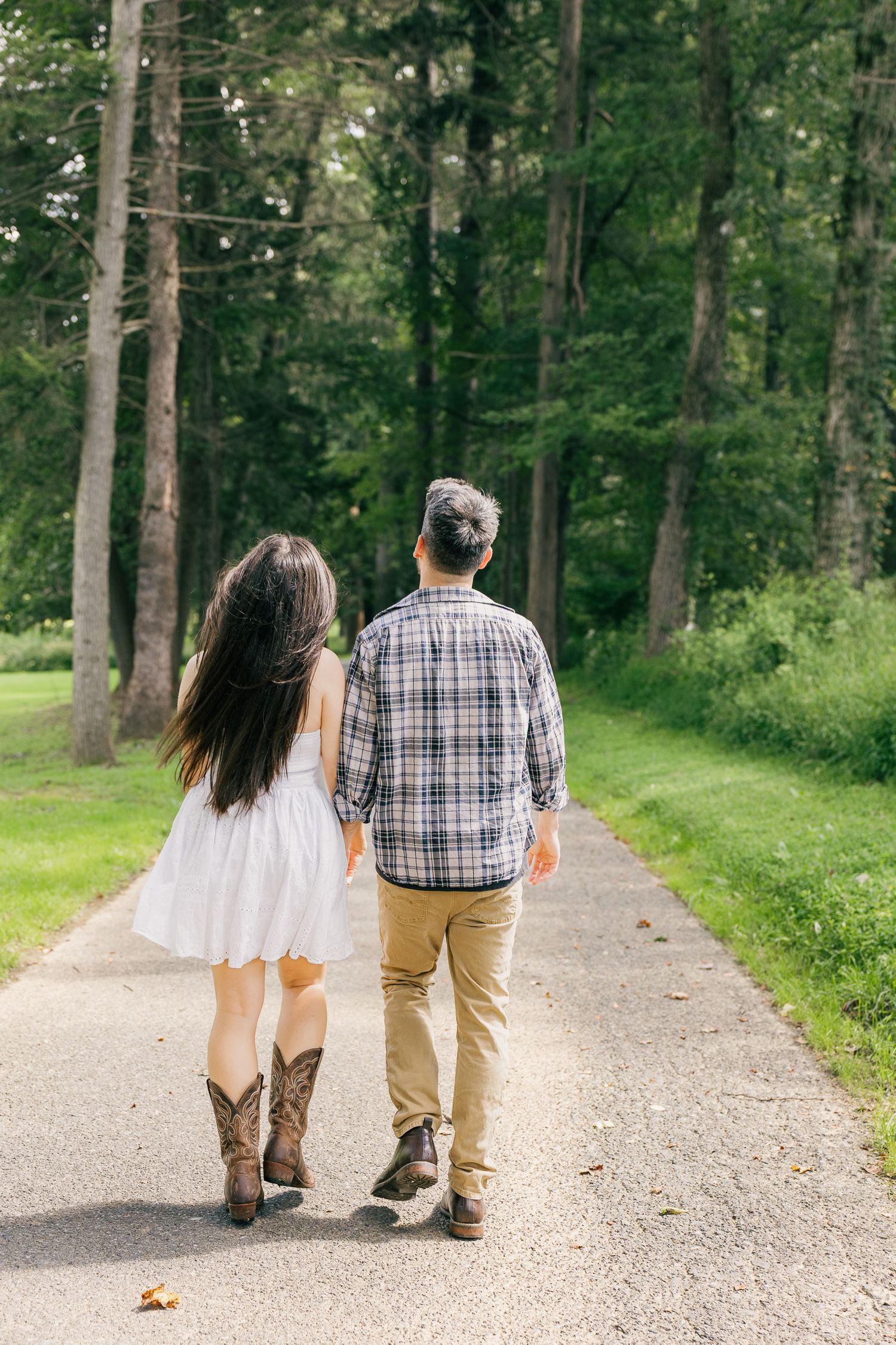Couple walking hand in hand along a tree-lined path during an outdoor Pennsylvania couples photography engagement session