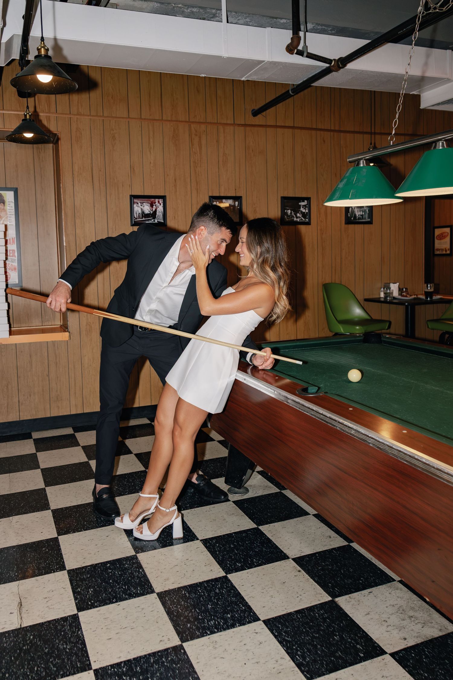 Couple posing beside a pool table in a Philadelphia bar during their editorial-inspired engagement photography session.