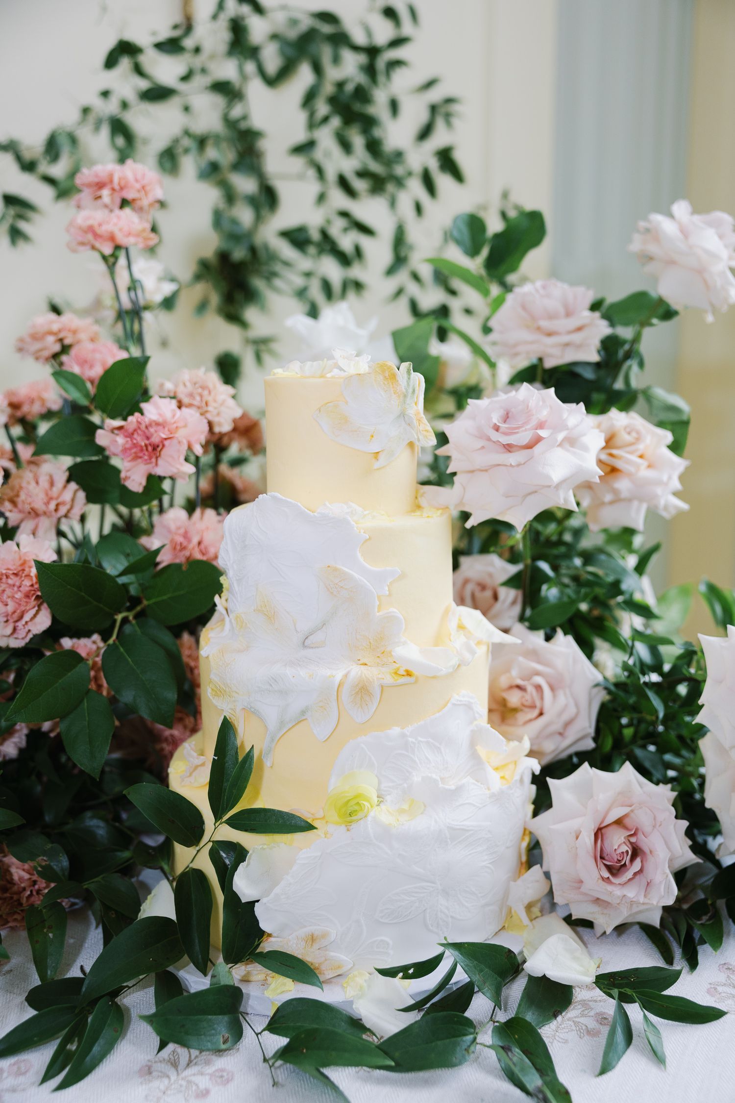 White wedding cake surrounded by pink and blush garden florals at the historic Elkins Estate in Pennsylvania.