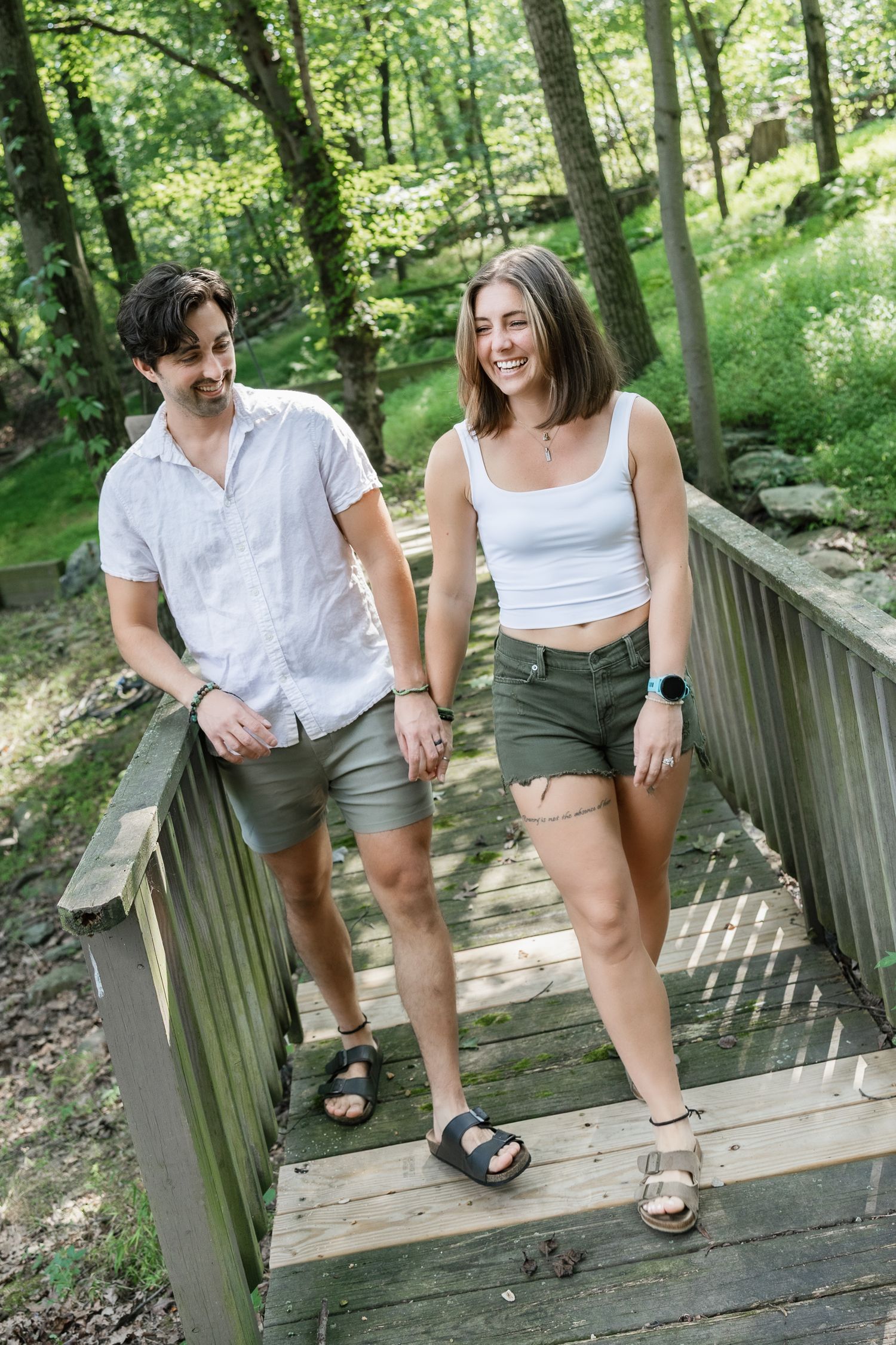 Couple walking hand in hand across a wooded bridge during a Pennsylvania couples Photography Session.
