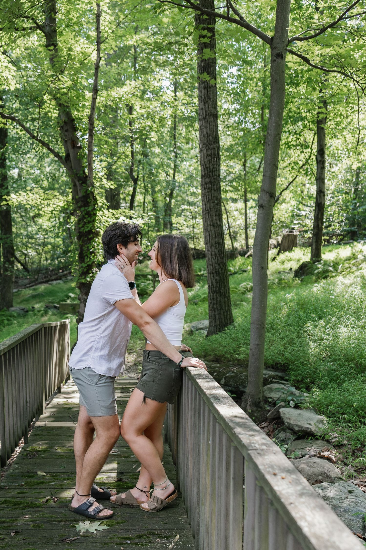 Couple sharing a playful moment on a wooded bridge during an outdoor couples photography session in Pennsylvania