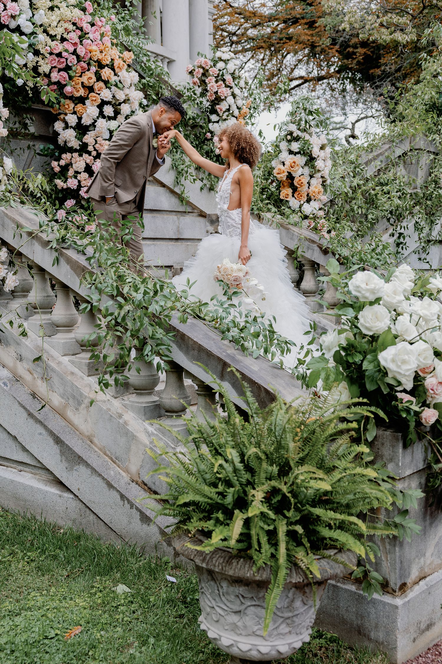 Romantic floral wedding installation along the historic staircase at Elkins Estate in Elkins Park, Pennsylvania, with lush white and blush f