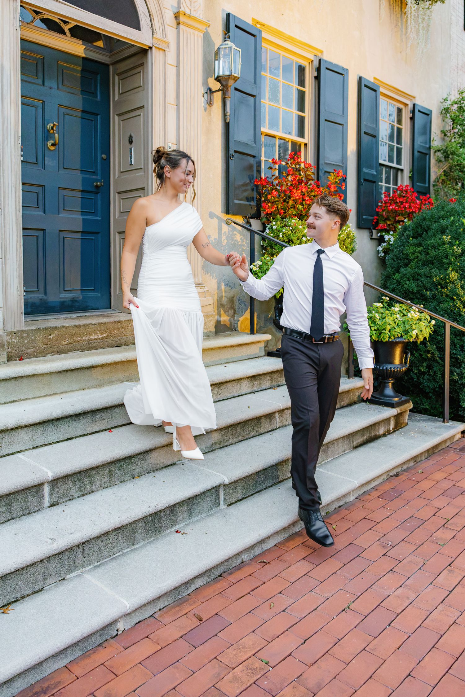 Engaged couple walking together outside Conestoga House and Gardens in Lancaster, Pennsylvania, surrounded by the colorful historic architec