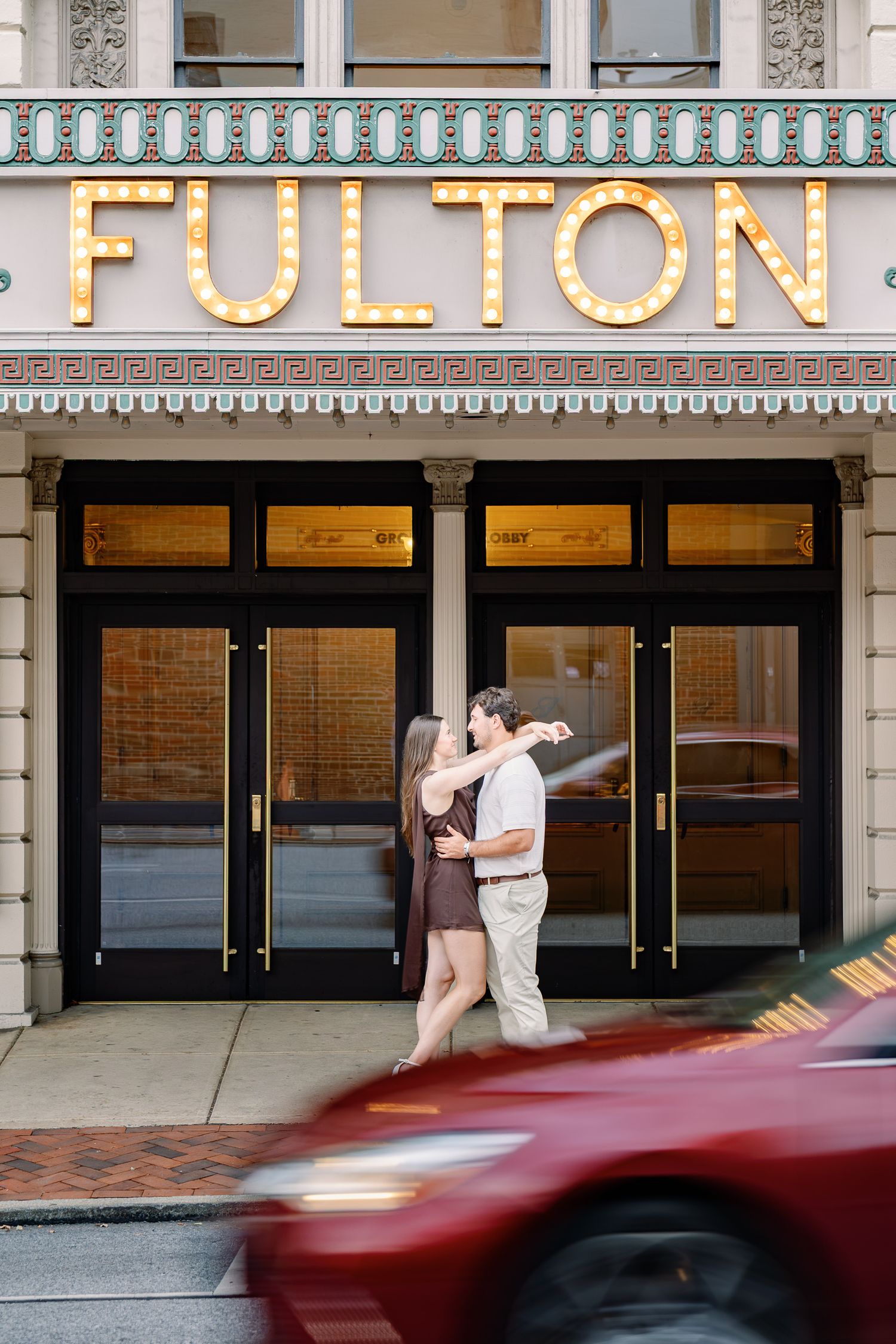 Couple embracing outside the historic Fulton Theatre during an engagement photography session in downtown Lancaster, Pennsylvania.