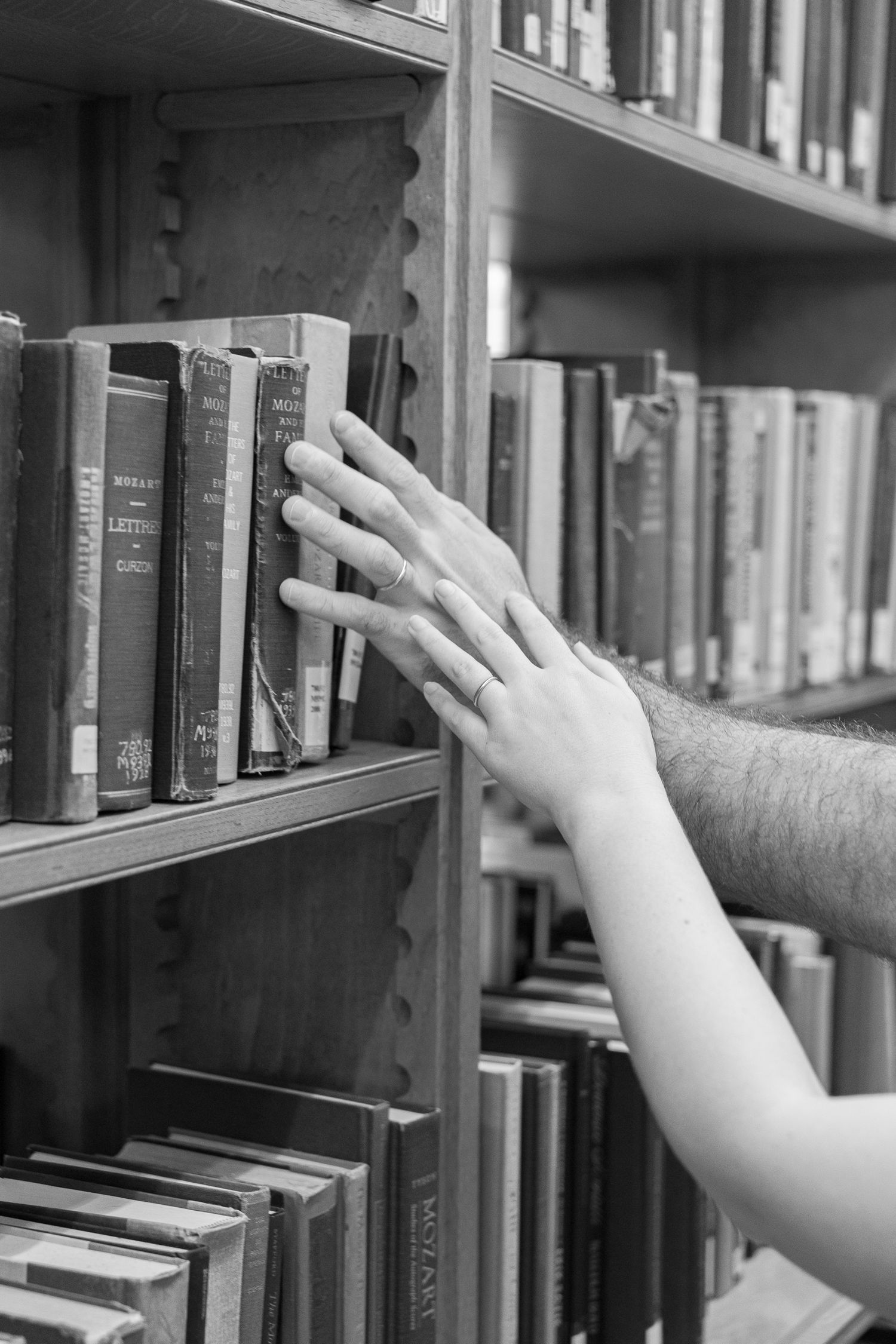 Black and white detail of a hand reaching for a book inside historic Linderman Library at Lehigh University in Pennsylvania.