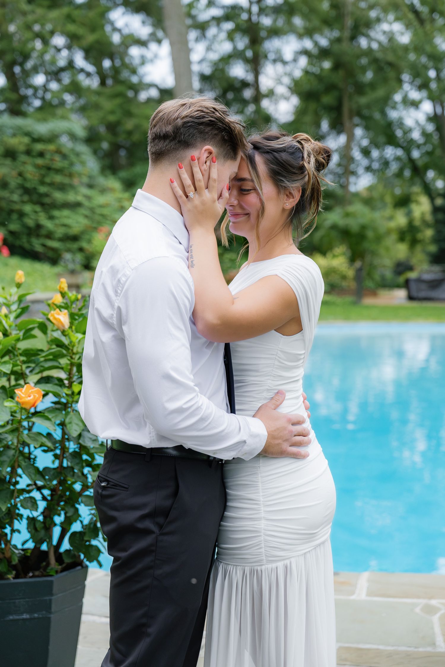 Romantic engagement portrait of a couple sharing a kiss beside the pool at Conestoga House and Gardens in Lancaster, PA.