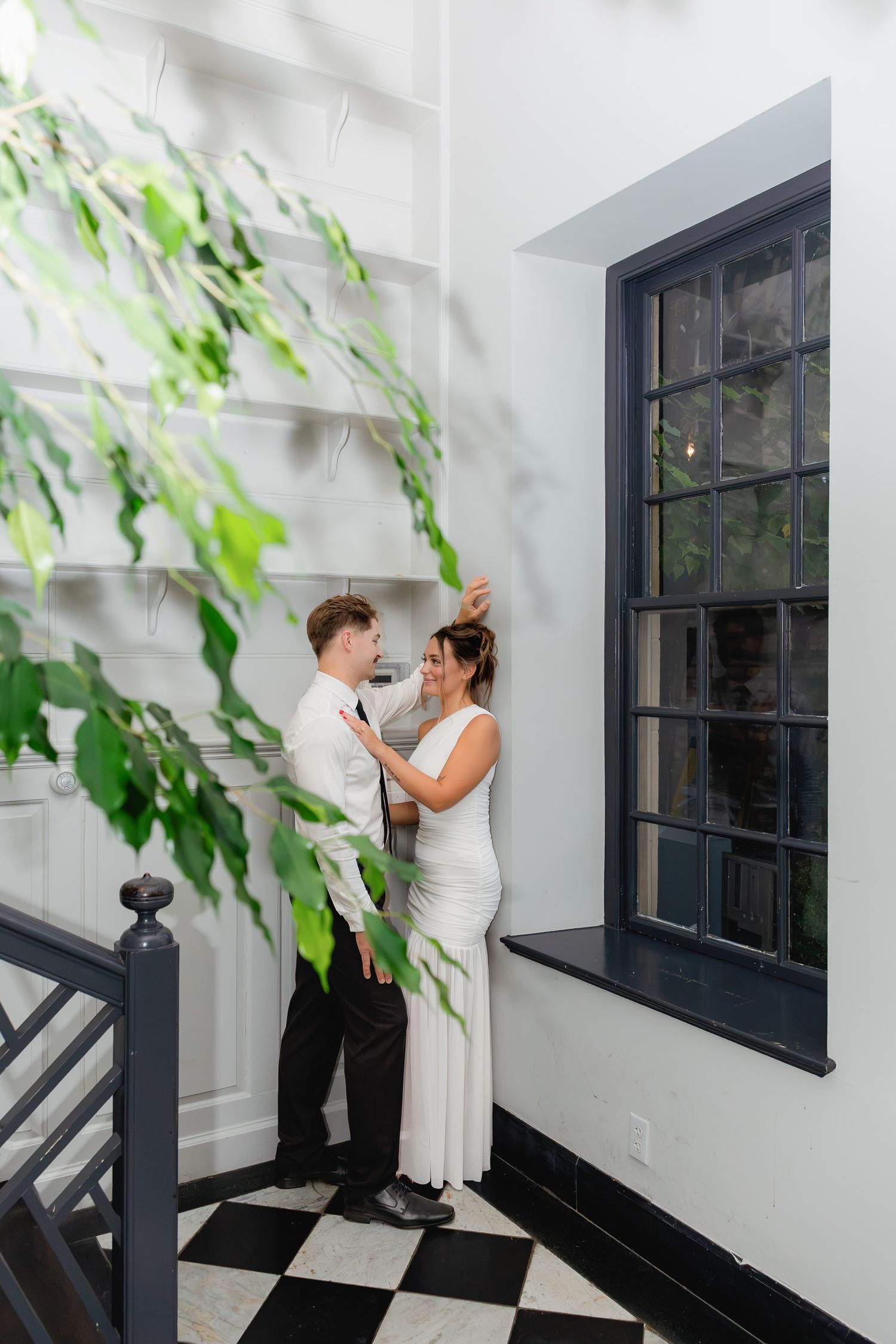 Engaged couple embracing beside the black and white tiled walkway at Conestoga House and Gardens during an elegant engagement session in Lan