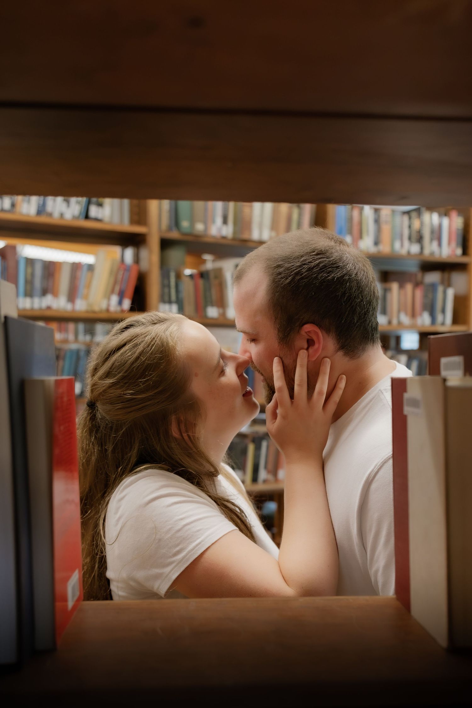 Couple sharing an intimate moment among the books during a couples photography session at Linderman Library in Bethlehem PA