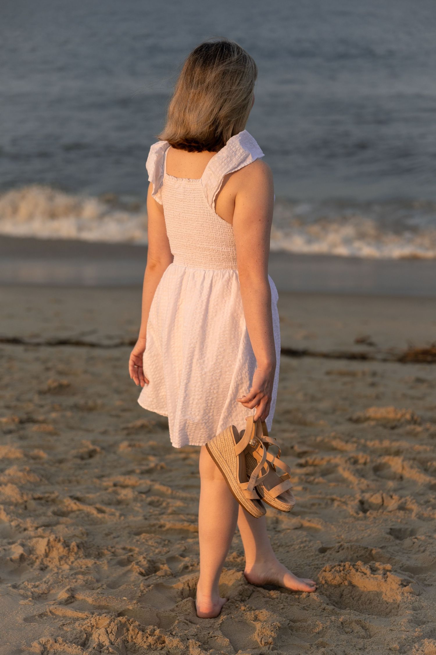 Woman walking along the beach at sunset during a relaxed lifestyle portrait photography session