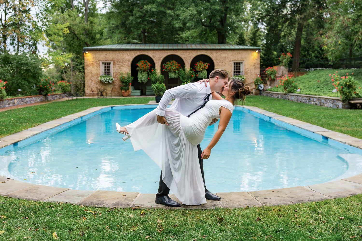 Engaged couple embracing in front of the pool at Conestoga House and Gardens, surrounded by the historic estate and gardens in Lancaster, Pe