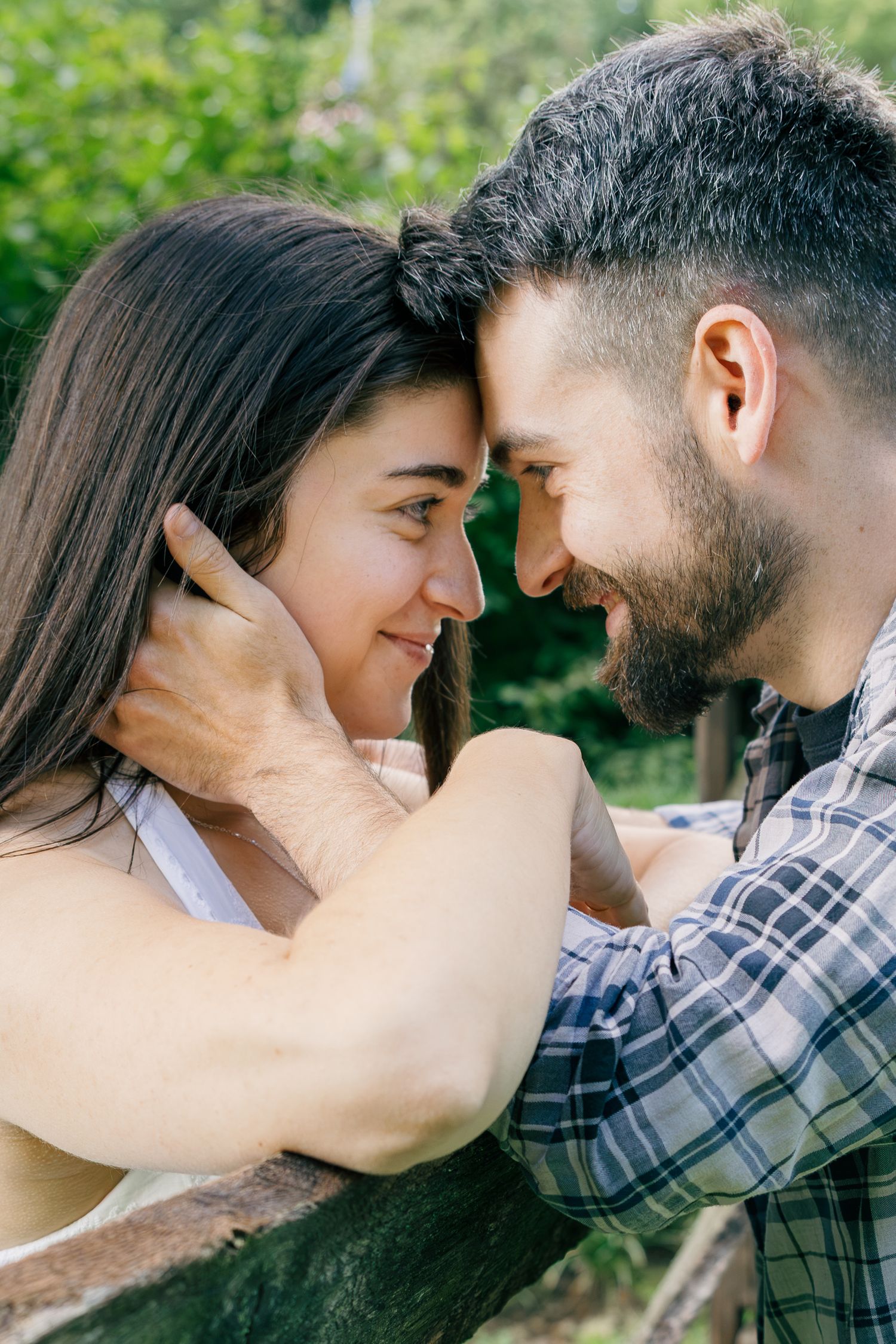 Couple sharing an intimate moment surrounded by greenery during an outdoor engagement photography session in Pennsylvania.