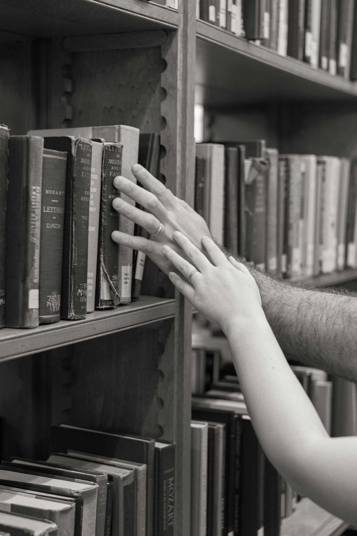 Black and white detail of a hand browsing books inside historic Linderman Library in Bethlehem Pennsylvania