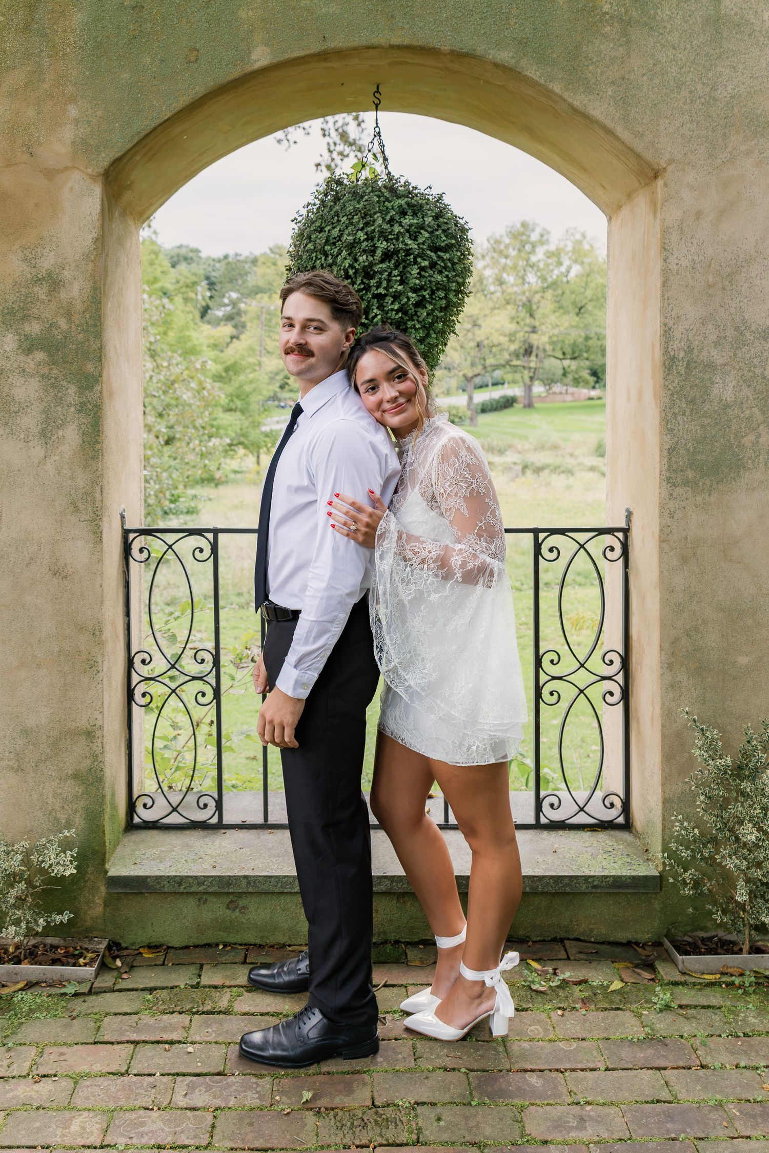 Engaged couple embracing beneath a garden archway at Conestoga House and Gardens during their Lancaster, Pennsylvania engagement session.