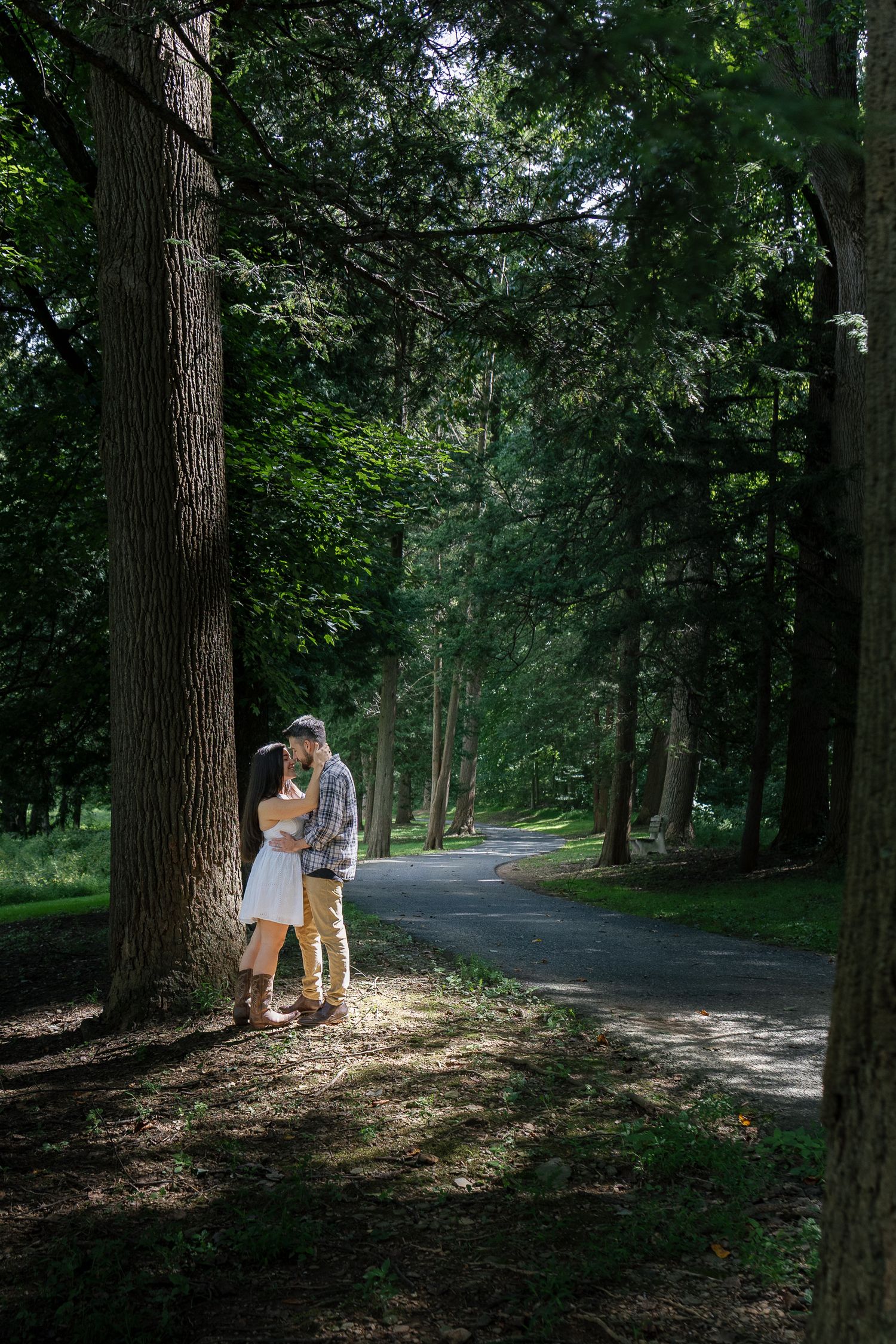 Couple walking together along a tree-lined path during a romantic outdoor engagement photography session in Pennsylvania.