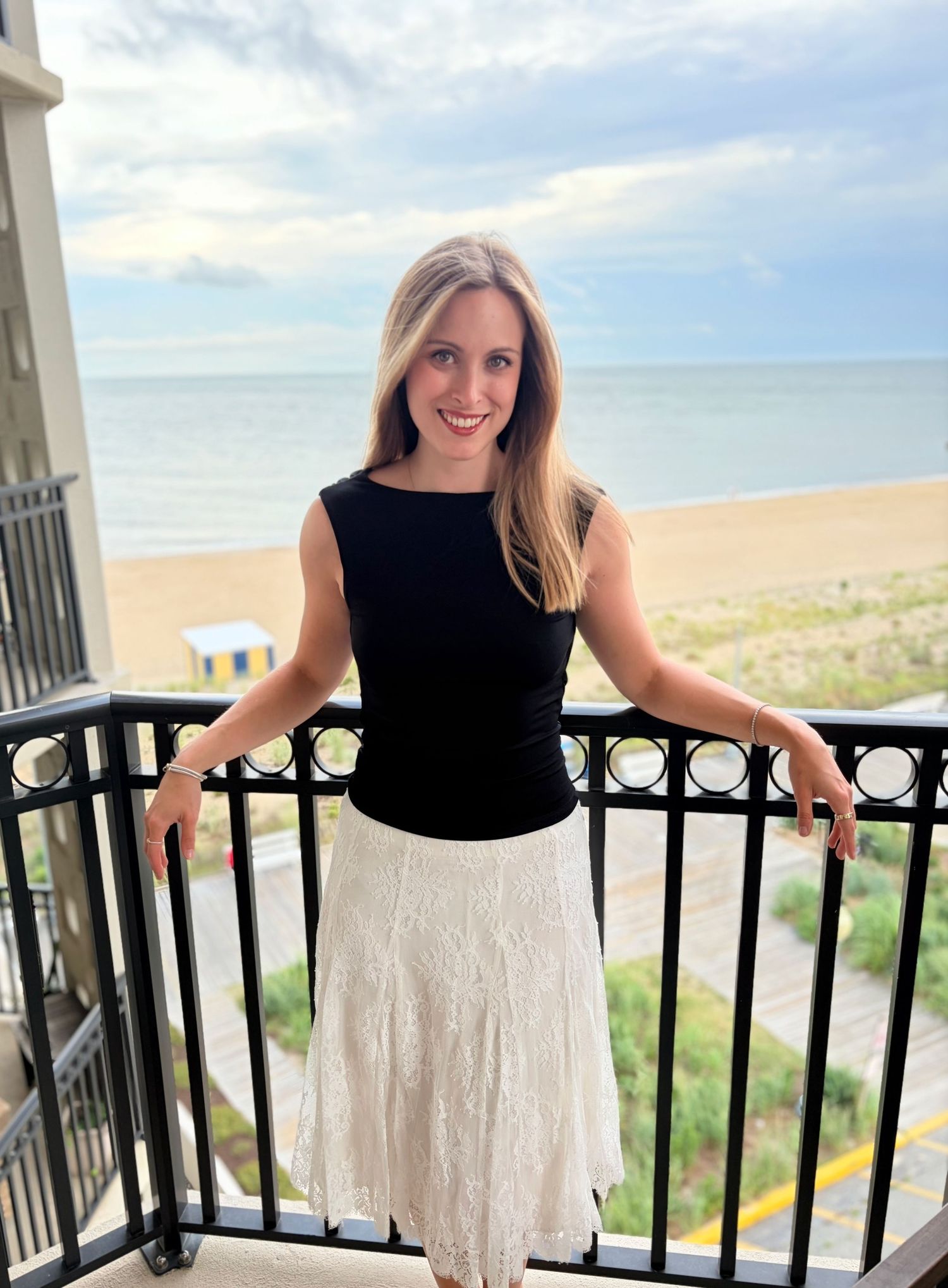Woman posing on a balcony overlooking the ocean during a natural light lifestyle portrait photography session
