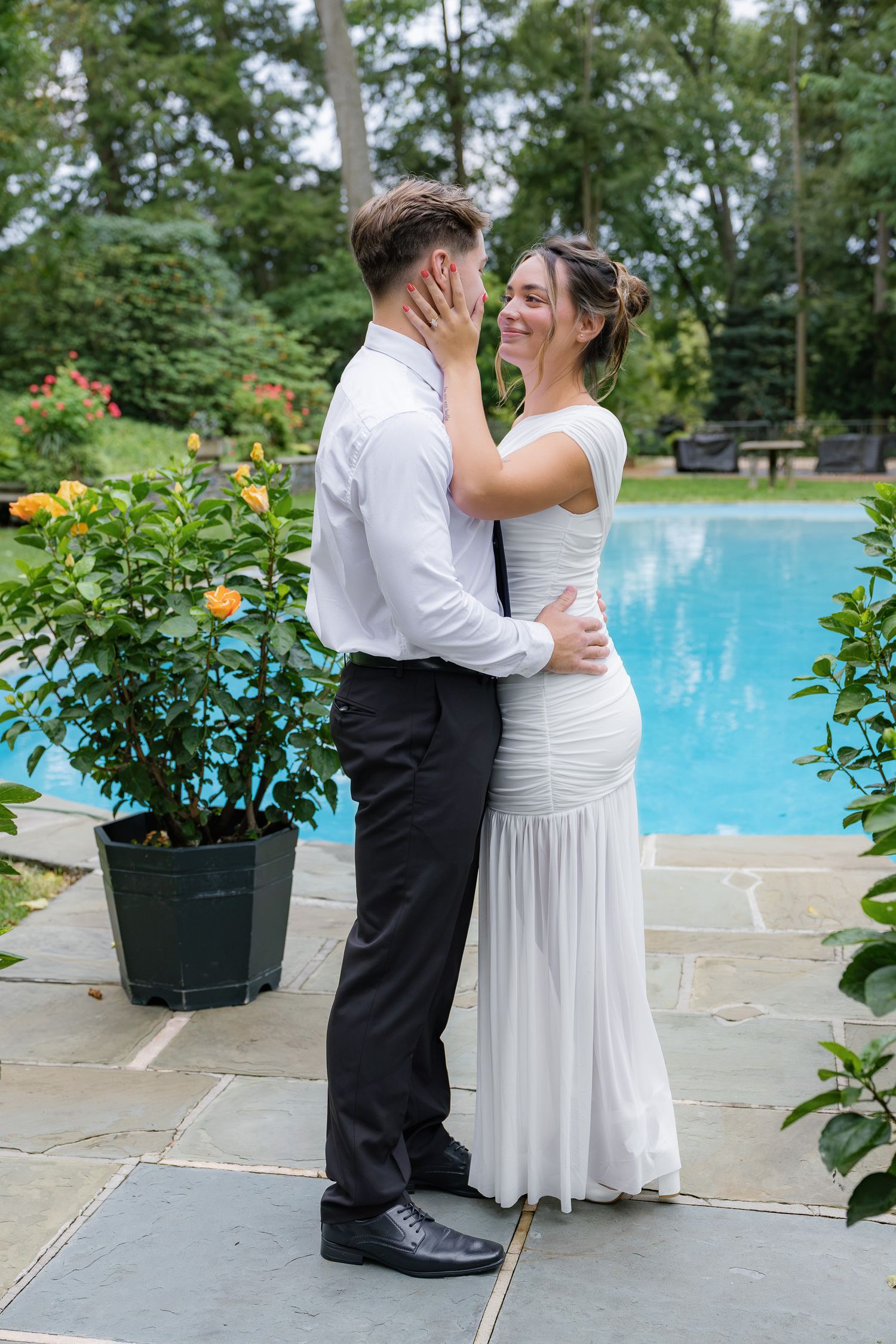 Engaged couple standing together beside the pool and lush gardens at Conestoga House and Gardens during their Lancaster, Pennsylvania engage