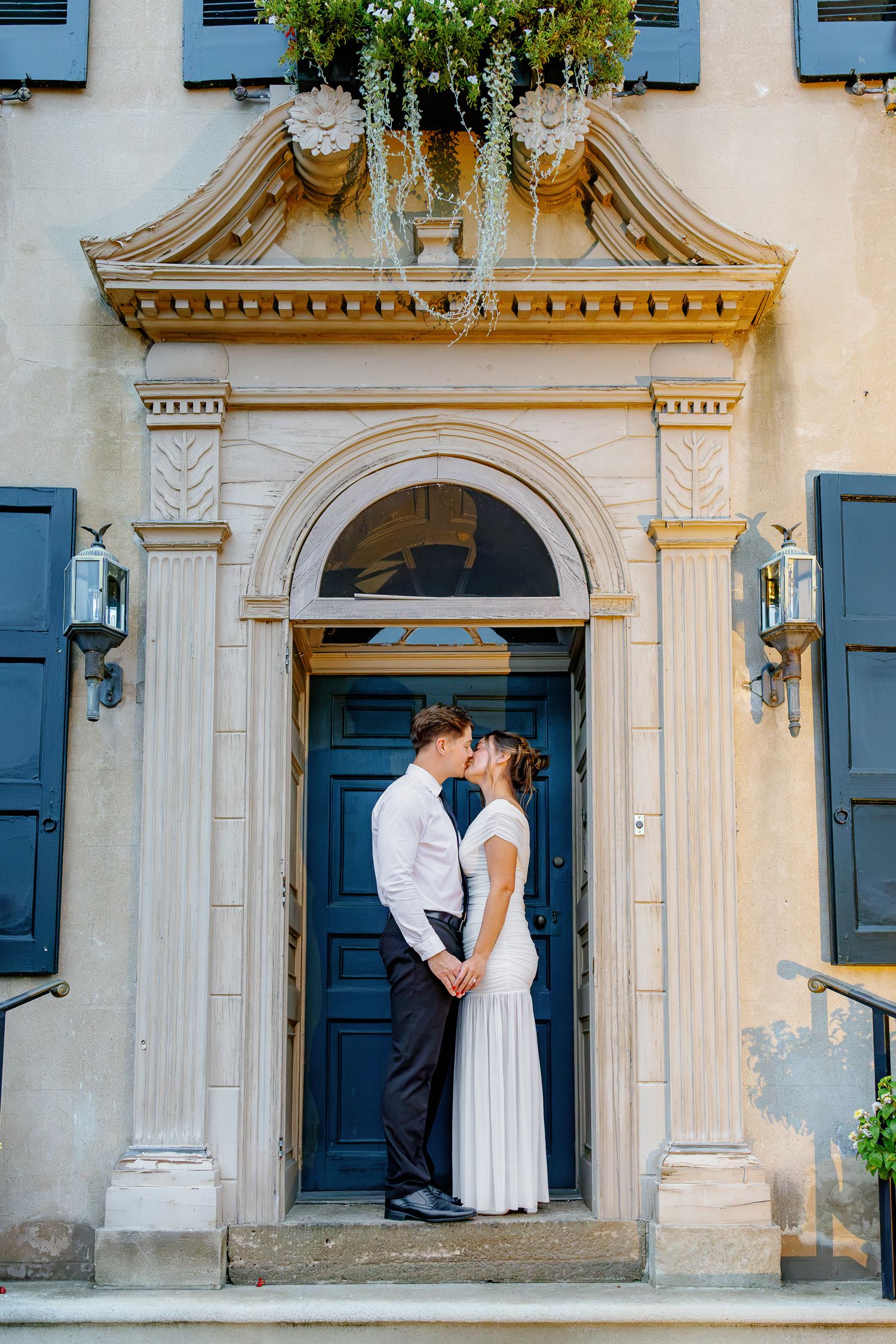 Engaged couple embracing in the ornate blue doorway at Conestoga House and Gardens during an elegant engagement session in Lancaster, Pennsy