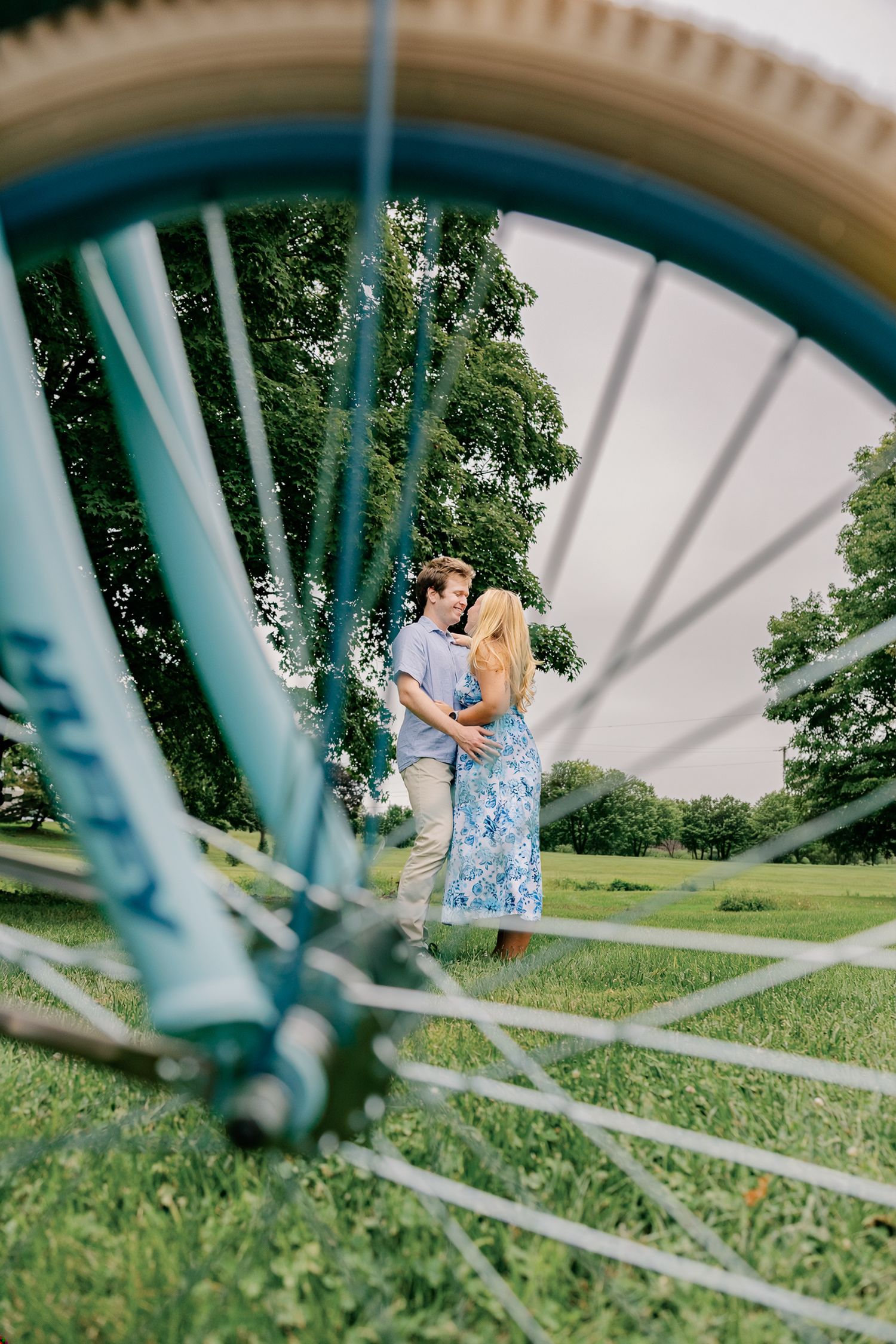 Couple photographed through a vintage bicycle wheel during an outdoor couples photography session in Lancaster, Pennsylvania