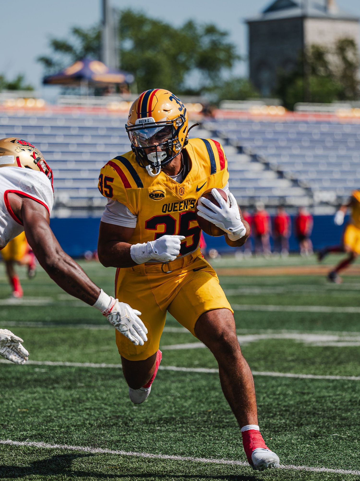 Queen's University number 25 runs with football during game.