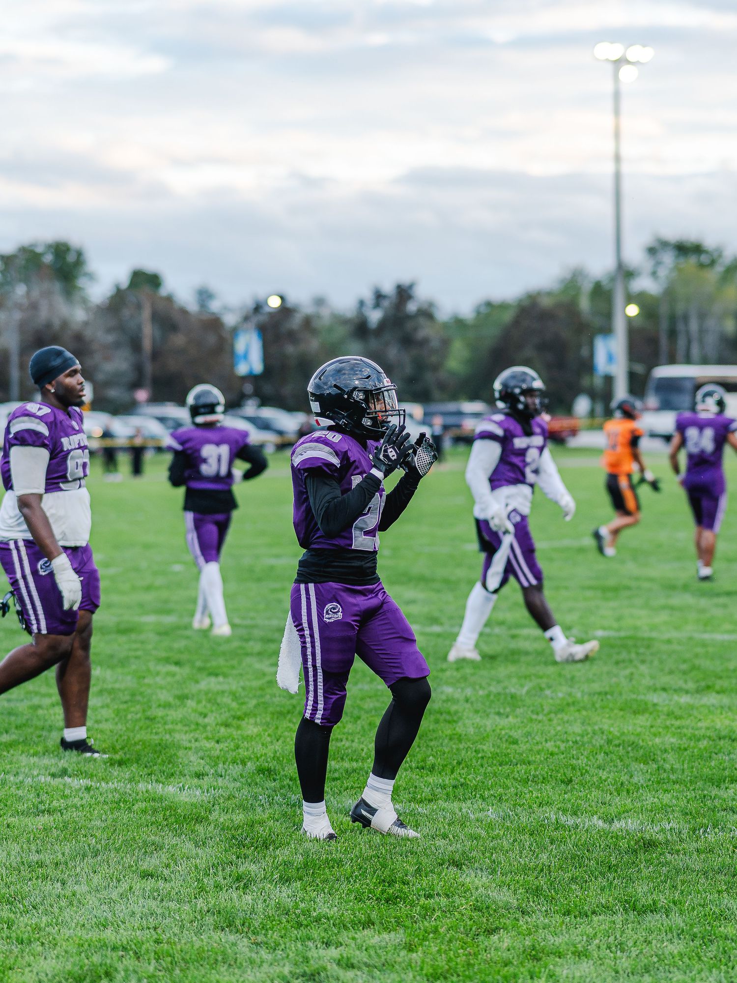 Riptides football players in purple uniforms warm up on green field before game.